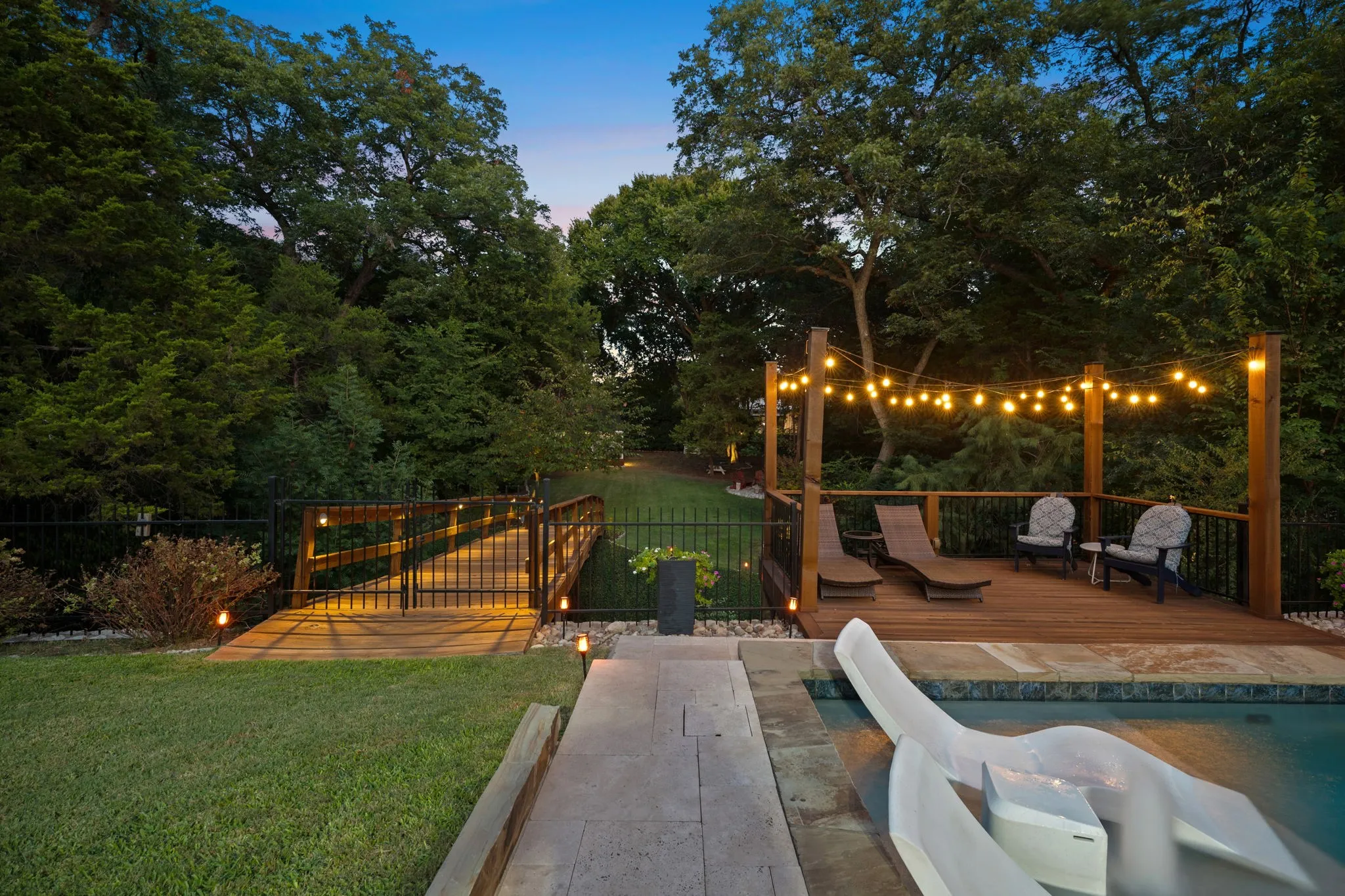 Deck next to the pool with seating area view of bridge to back of property