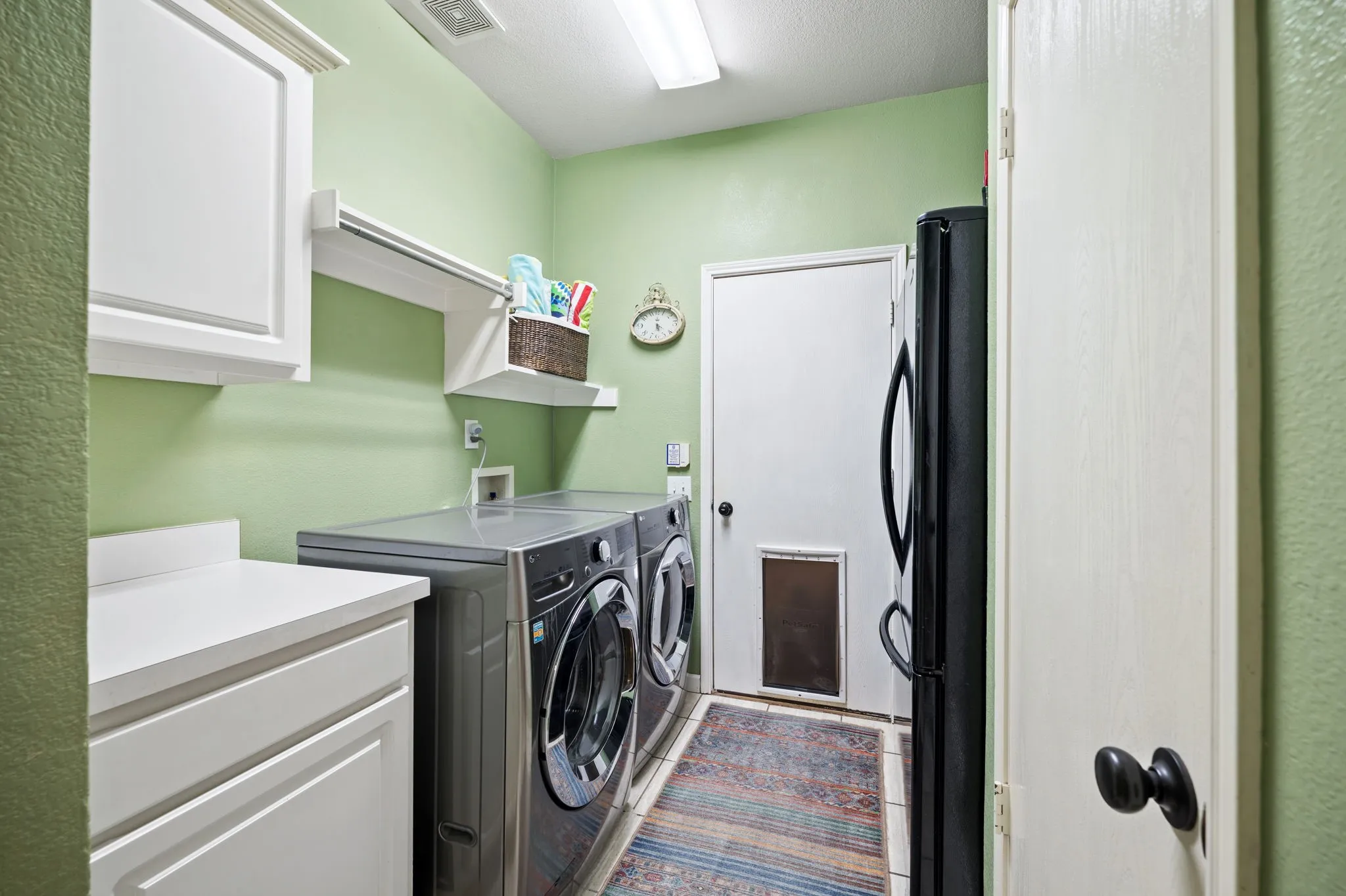 Spacious laundry room with cabinets with space for fridge