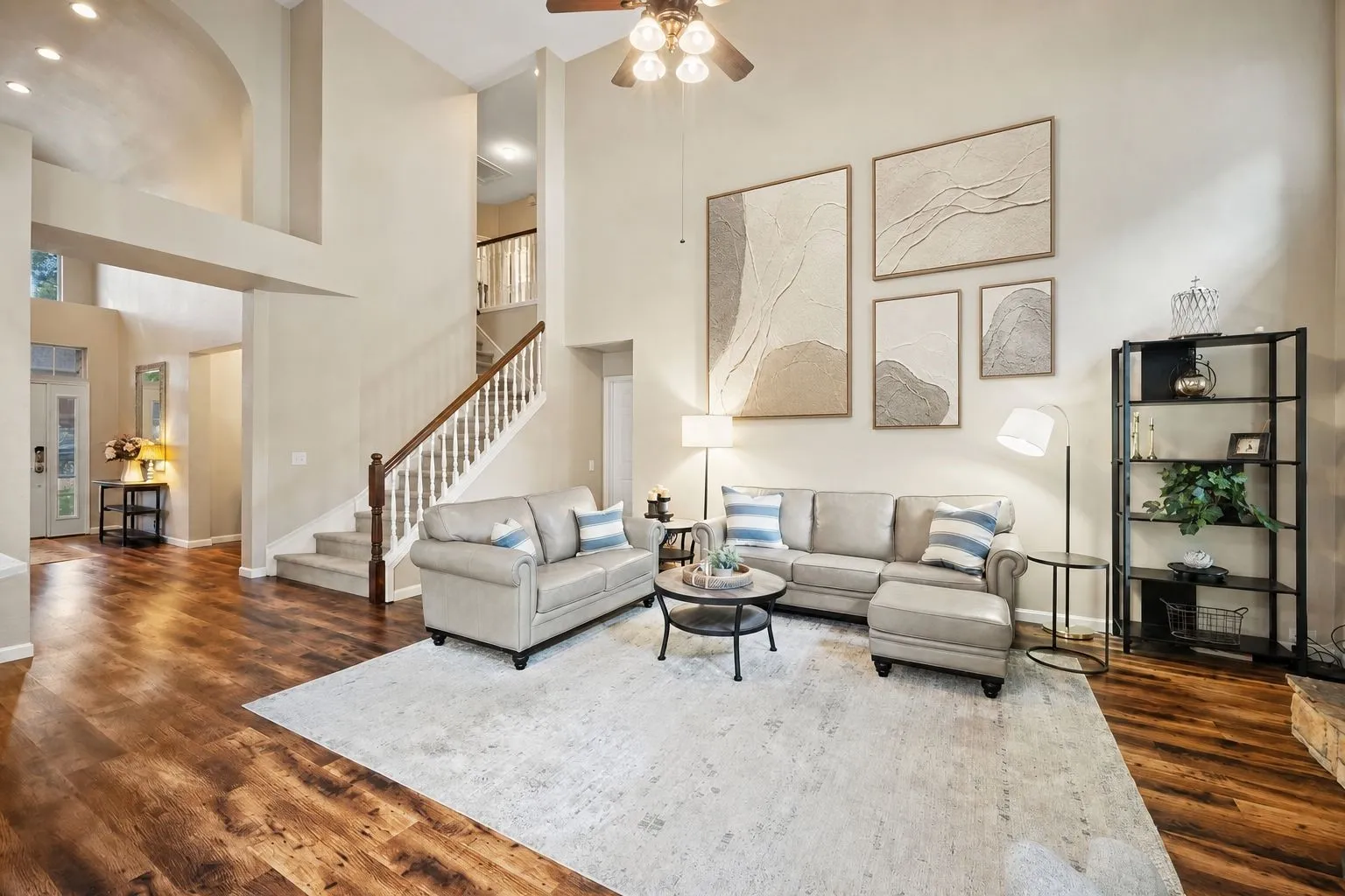 Vaulted ceiling, wood-finish flooring, staircase with wood handrail and white balusters, recessed lighting, and a ceiling fan