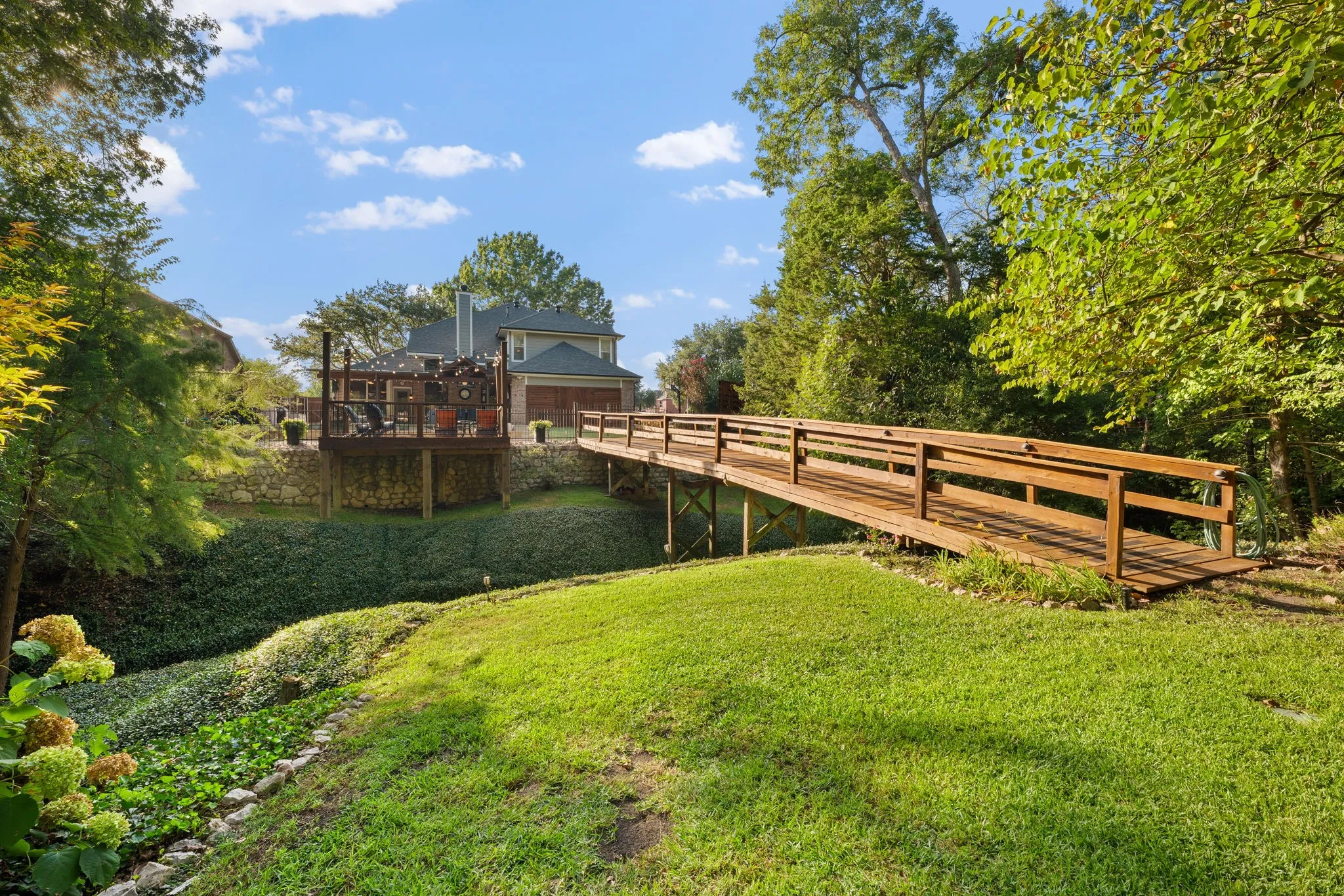 Expansive backyard featuring a manicured lawn, lush ground cover, and mature trees