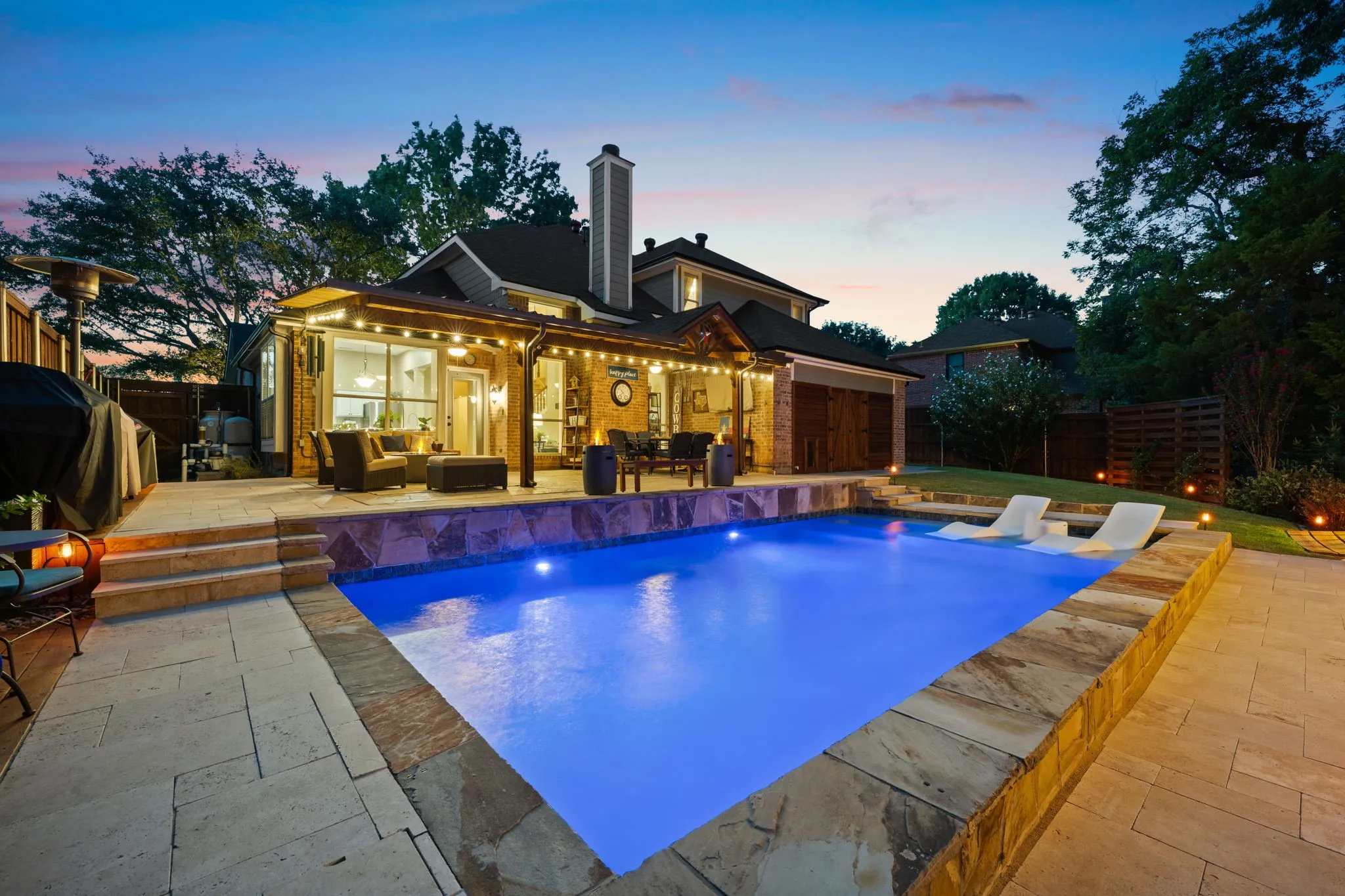 Resort-style pool with tanning ledge, covered patio with dining and seating areas
