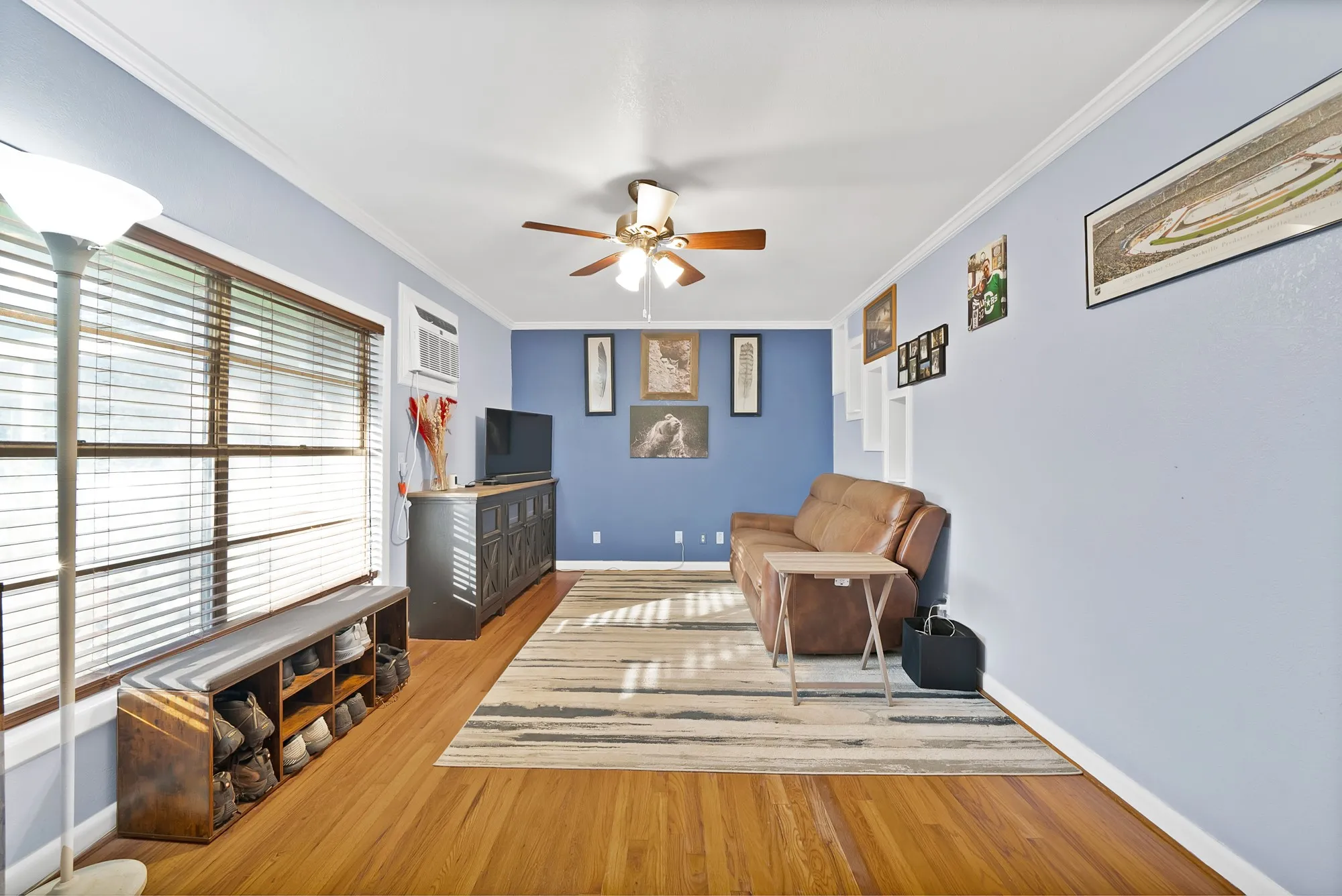 Hardwood flooring, crown molding, ceiling fan, window with blinds, and built-in shelving