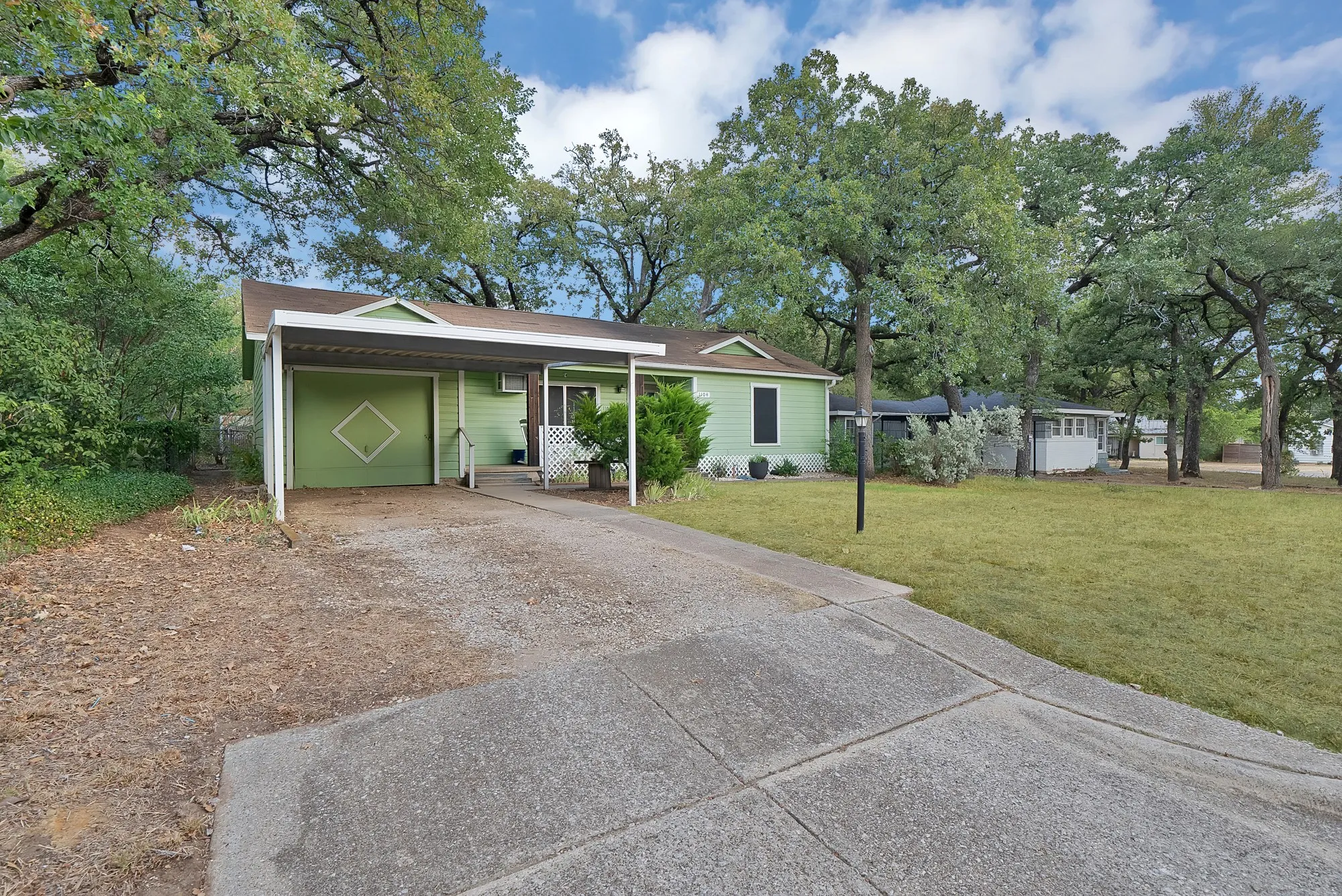 Single-story residence featuring a carport, exterior with light green siding, and a front porch