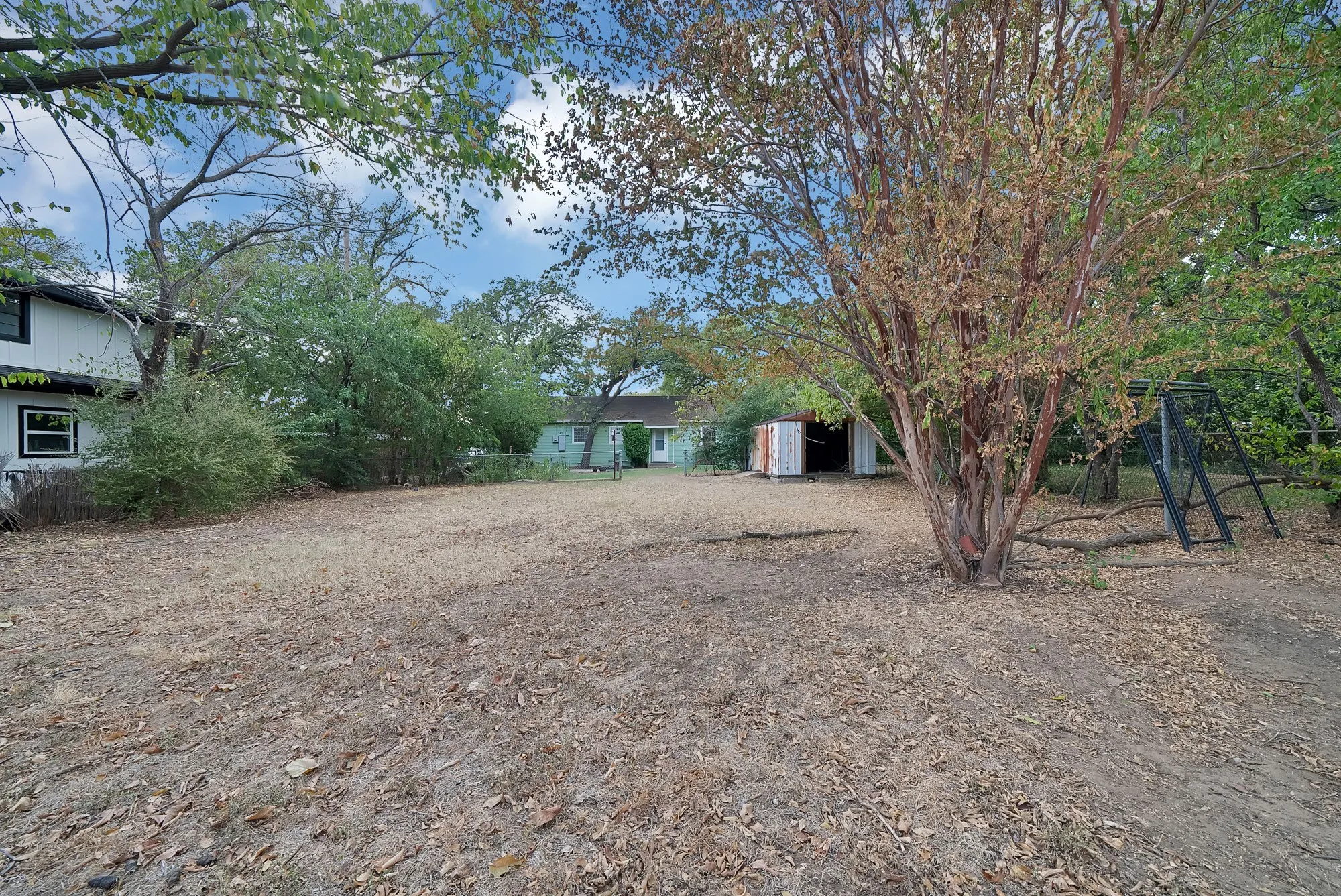 Expansive lot featuring mature trees and a detached shed