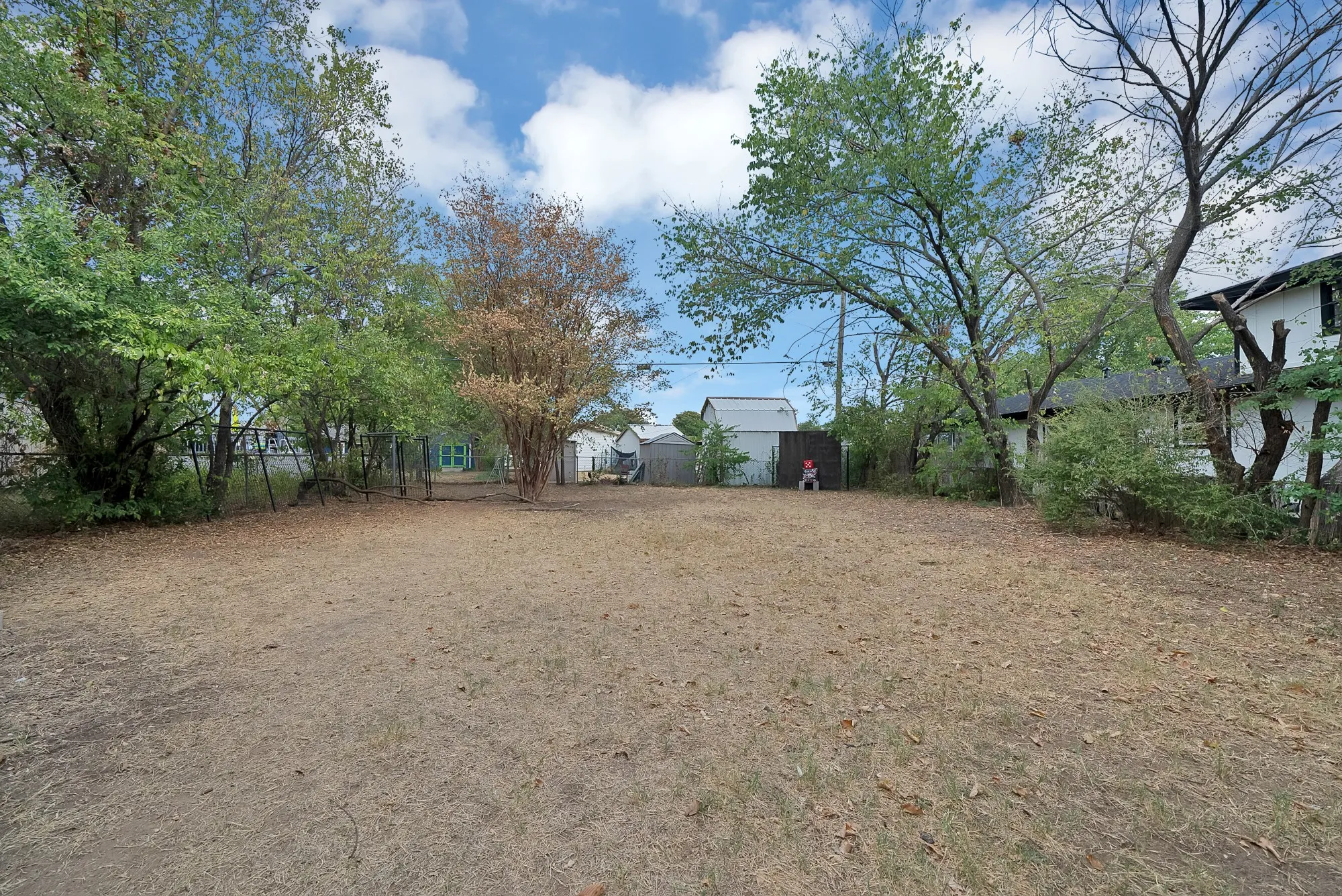 Expansive yard featuring mature trees and perimeter fencing