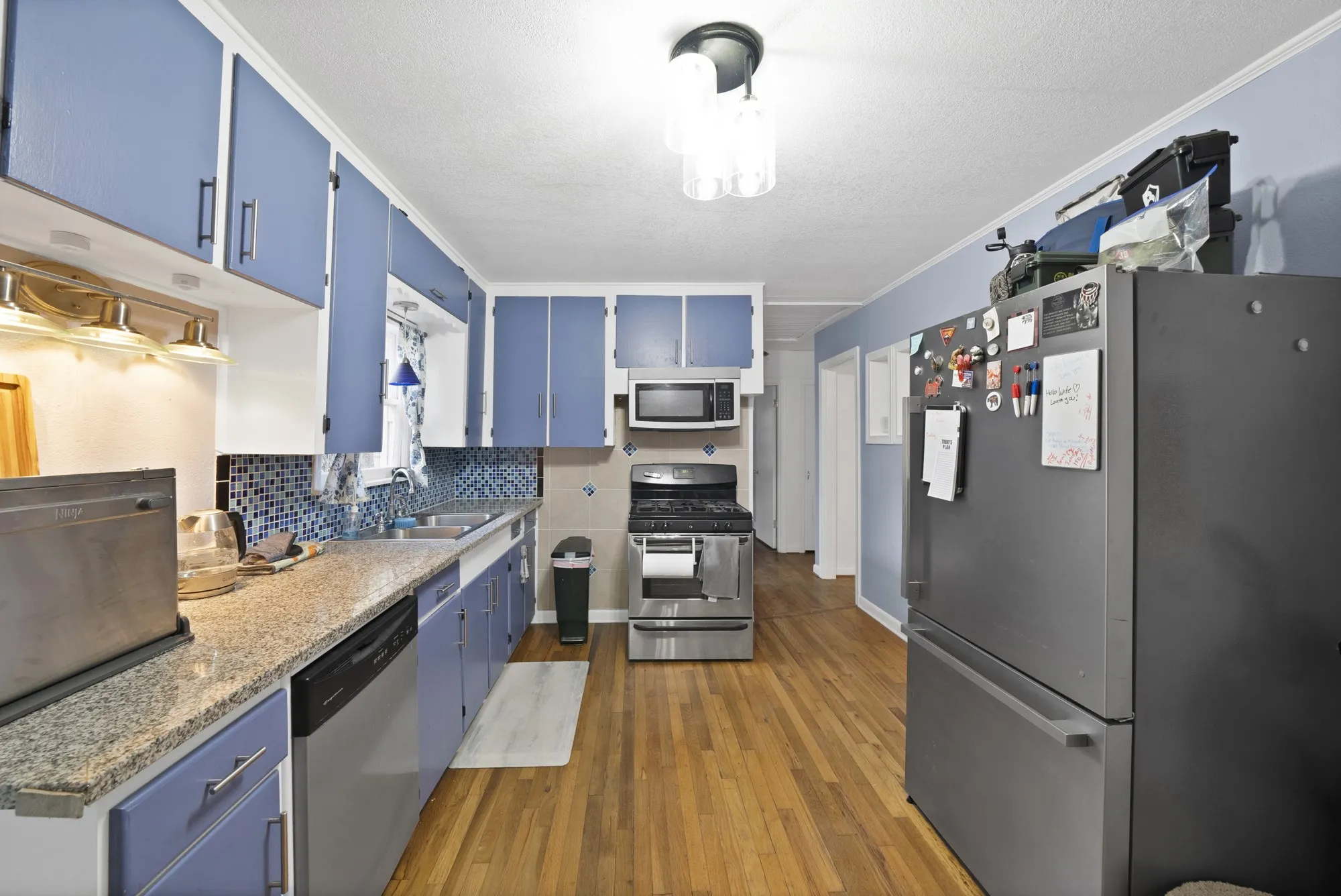 Kitchen featuring wood-finish flooring, light-toned countertops, tile backsplash, and stainless-steel appliances