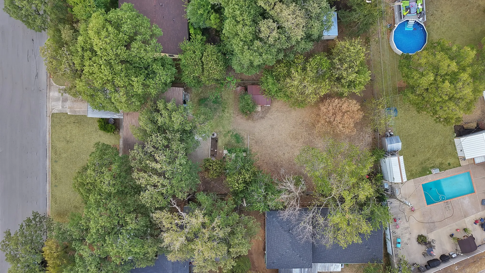 Mature trees and verdant landscaping frame the property, featuring a paved driveway and a distinct roofline