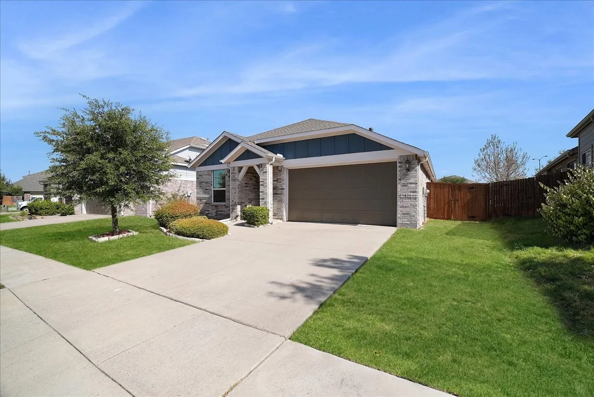 Brick and siding exterior with an attached garage, concrete driveway, and a wood privacy fence