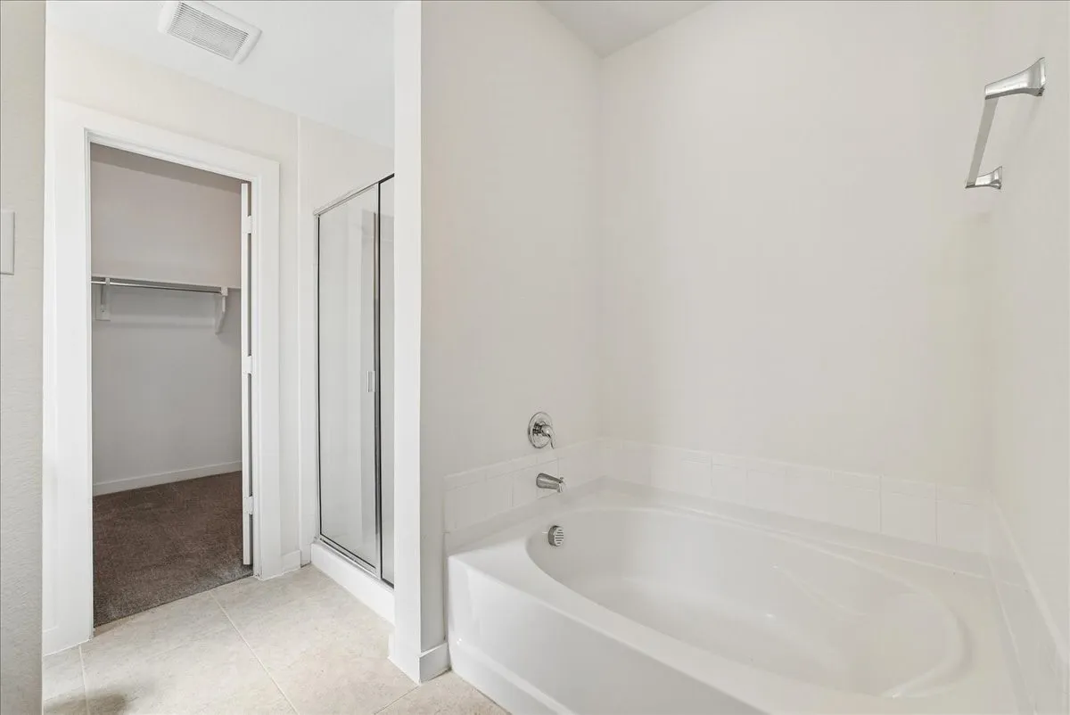 Soaking tub with a tile surround, glass-enclosed shower, and tile flooring