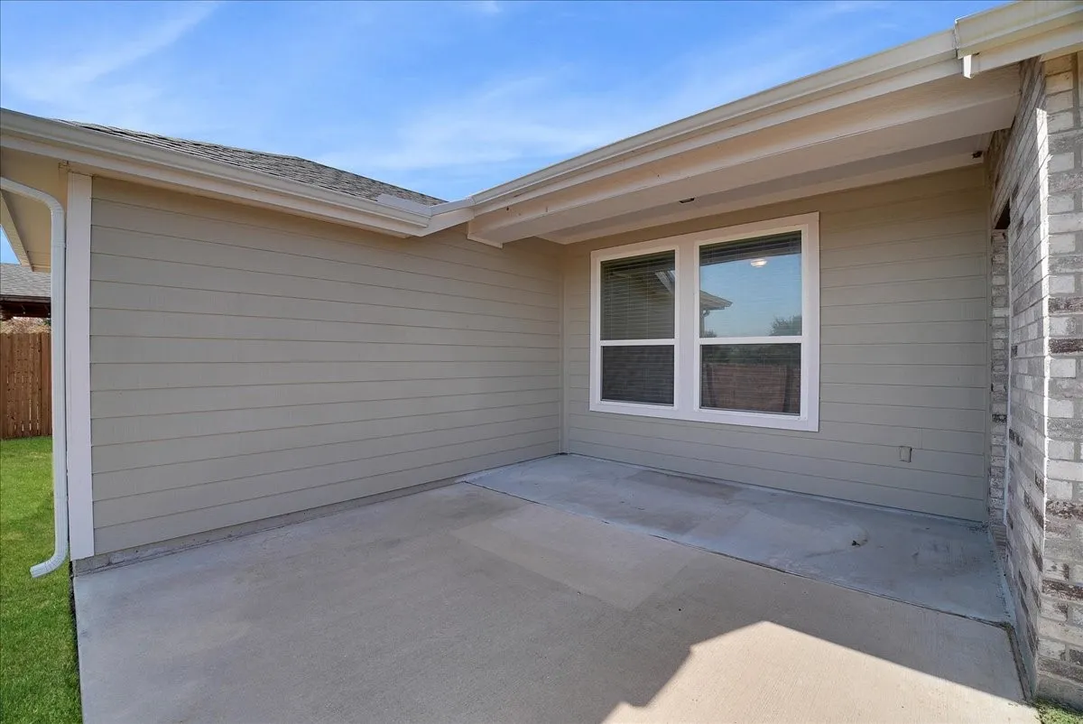 Covered concrete patio with horizontal siding and brick accent wall