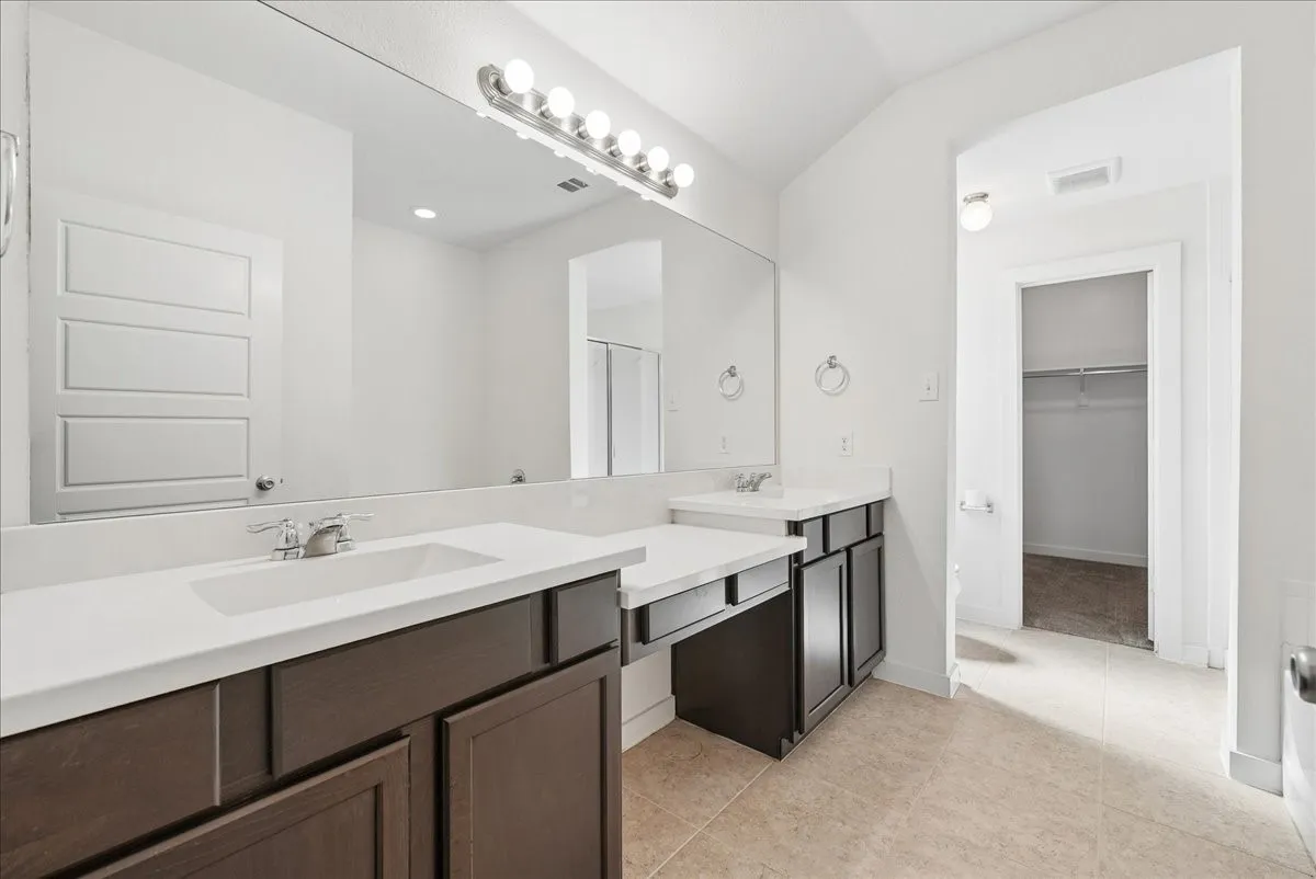 Dual vanity with white countertops, dark wood-finish cabinetry, and a large wall-mounted mirror