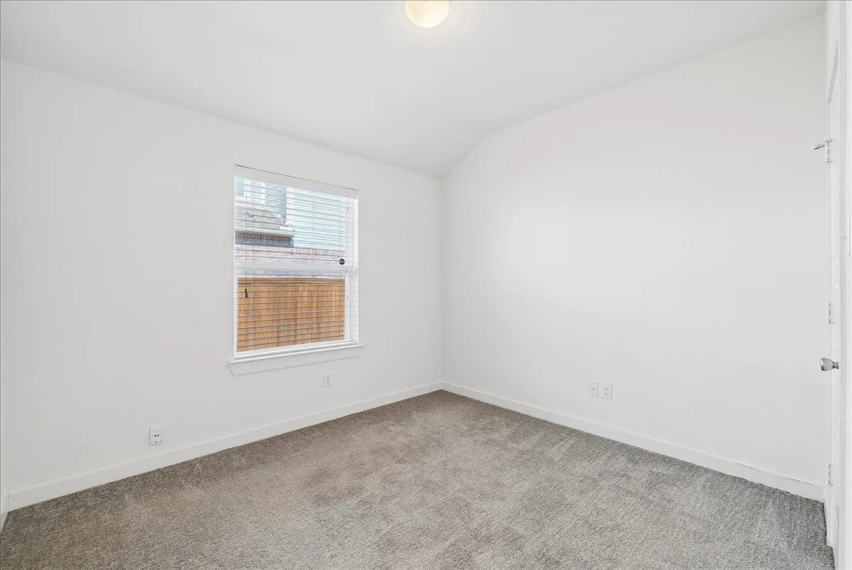 Neutral gray carpeting with white walls, a single window, and a flush-mount ceiling light