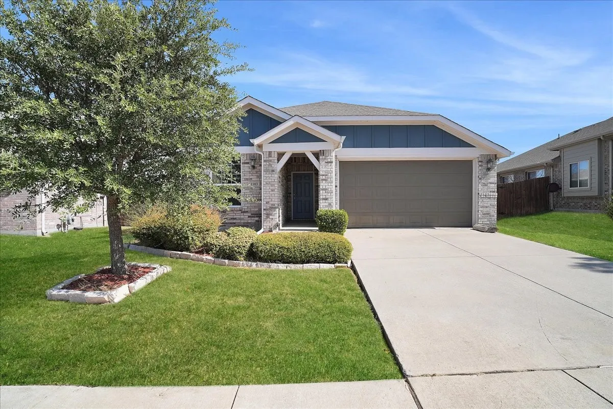 Exterior featuring a stone facade, gabled entry, attached garage, concrete driveway, and established front yard landscaping
