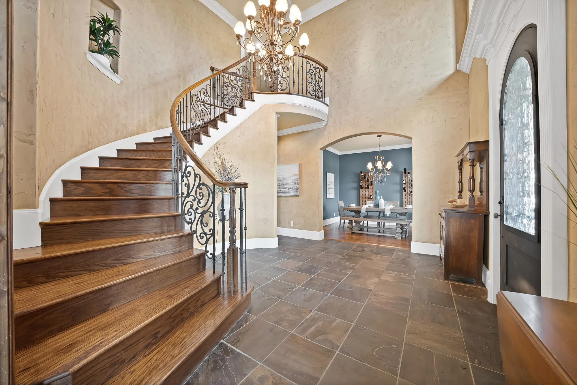 Two-story foyer featuring a curved staircase with wood treads, ornate wrought iron balusters, and a wood handrail
