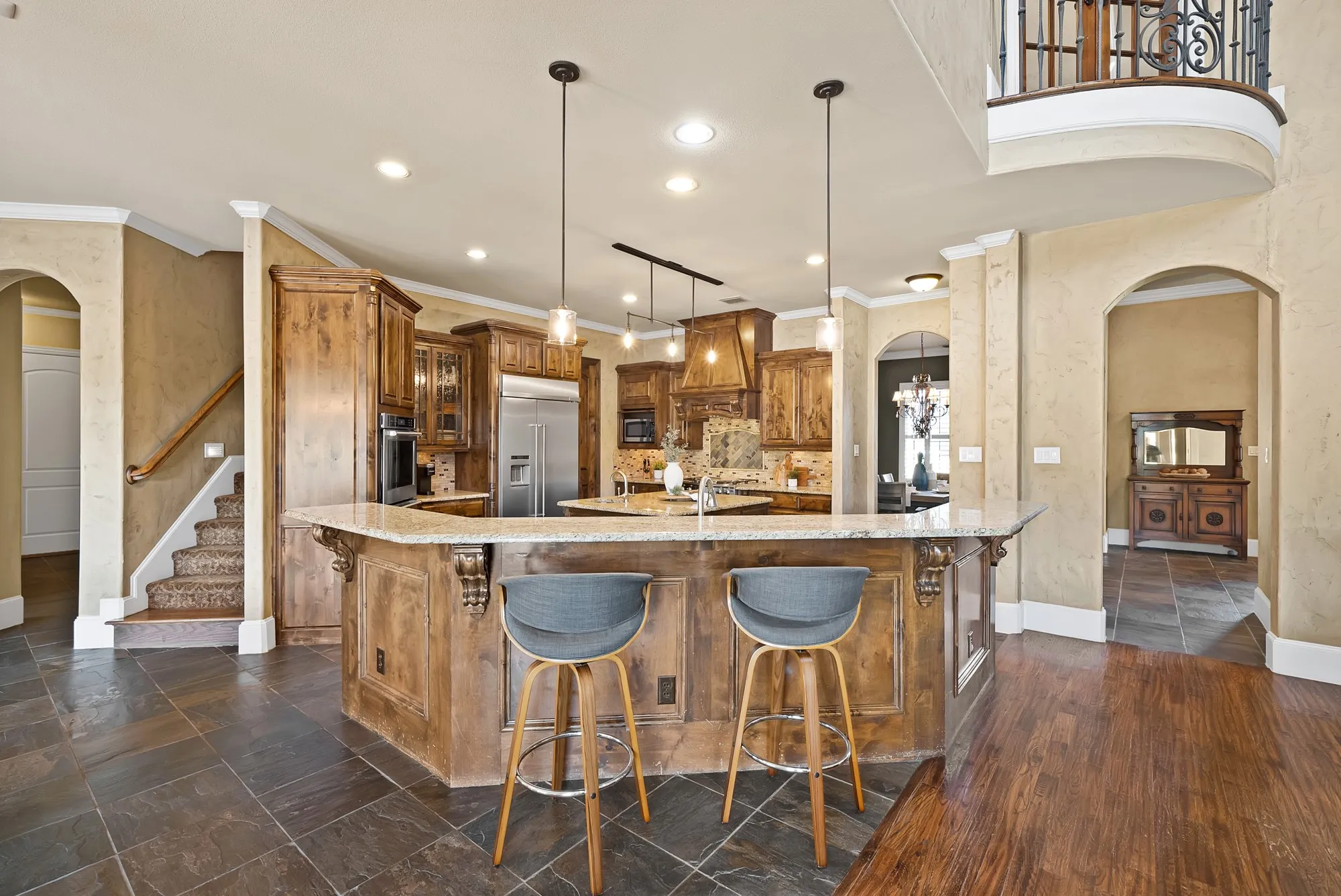 Kitchen island with stone countertop, wood-finish cabinetry, stainless steel appliances, and integrated cooktop