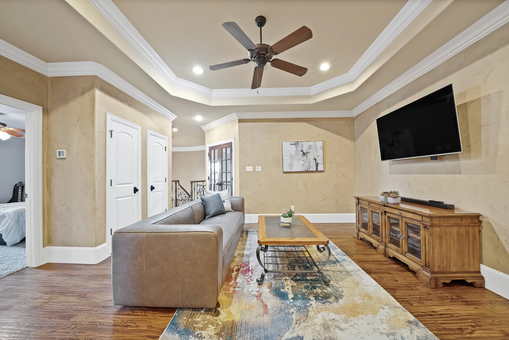 hand scraped hardwood floors, tray ceiling, recessed lighting, ceiling fan, and decorative crown molding
