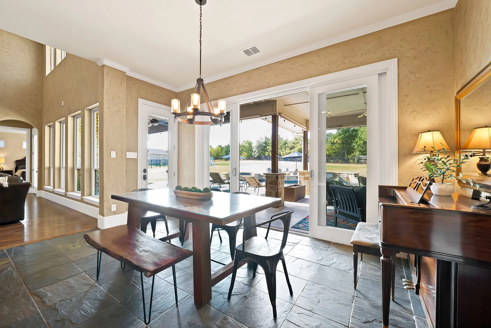 Slate tile flooring, patio access, high ceilings, large windows, and a modern chandelier