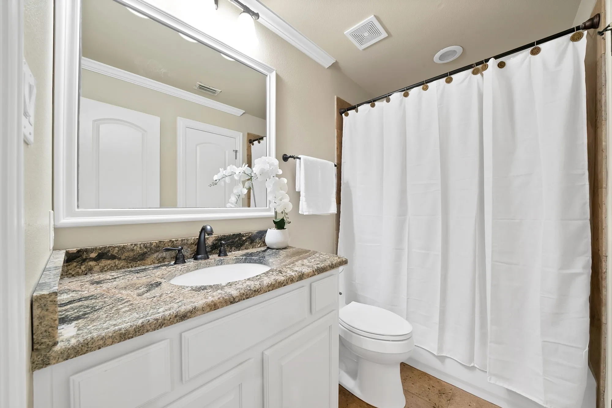 Vanity with a granite countertop, undermount sink, and dark bronze faucet