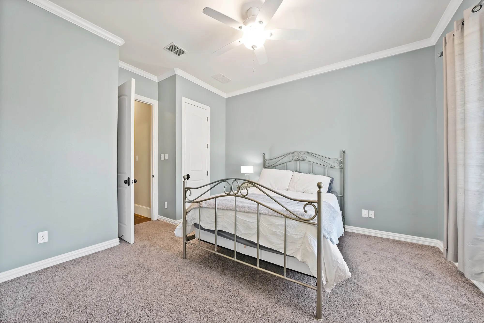 Textured carpeting, crown molding, ceiling fan with integrated lighting, and a paneled interior door