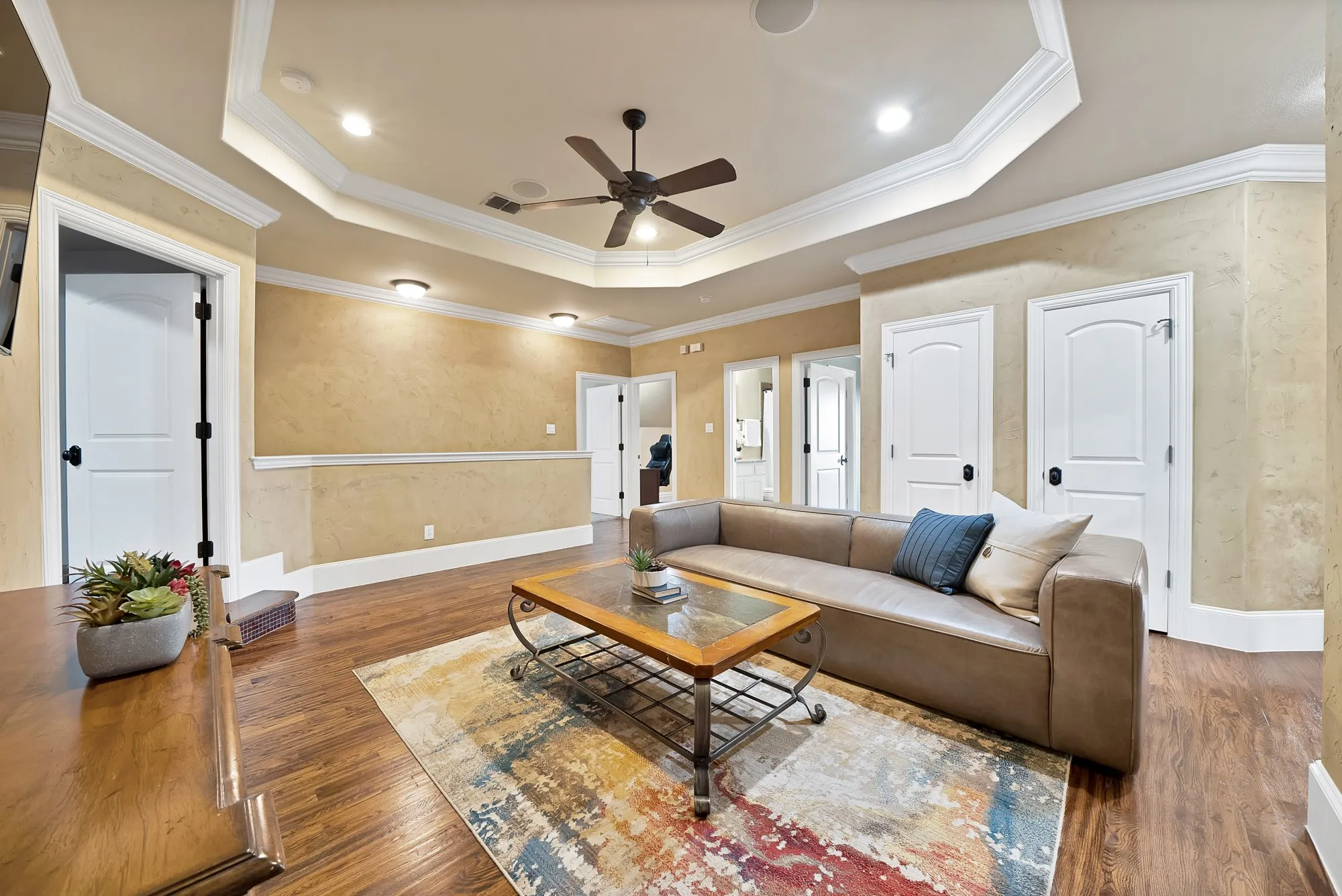 hand scraped hardwood floors throughout, tray ceiling with recessed lighting and a ceiling fan, and multiple white panel doors with dark hardware