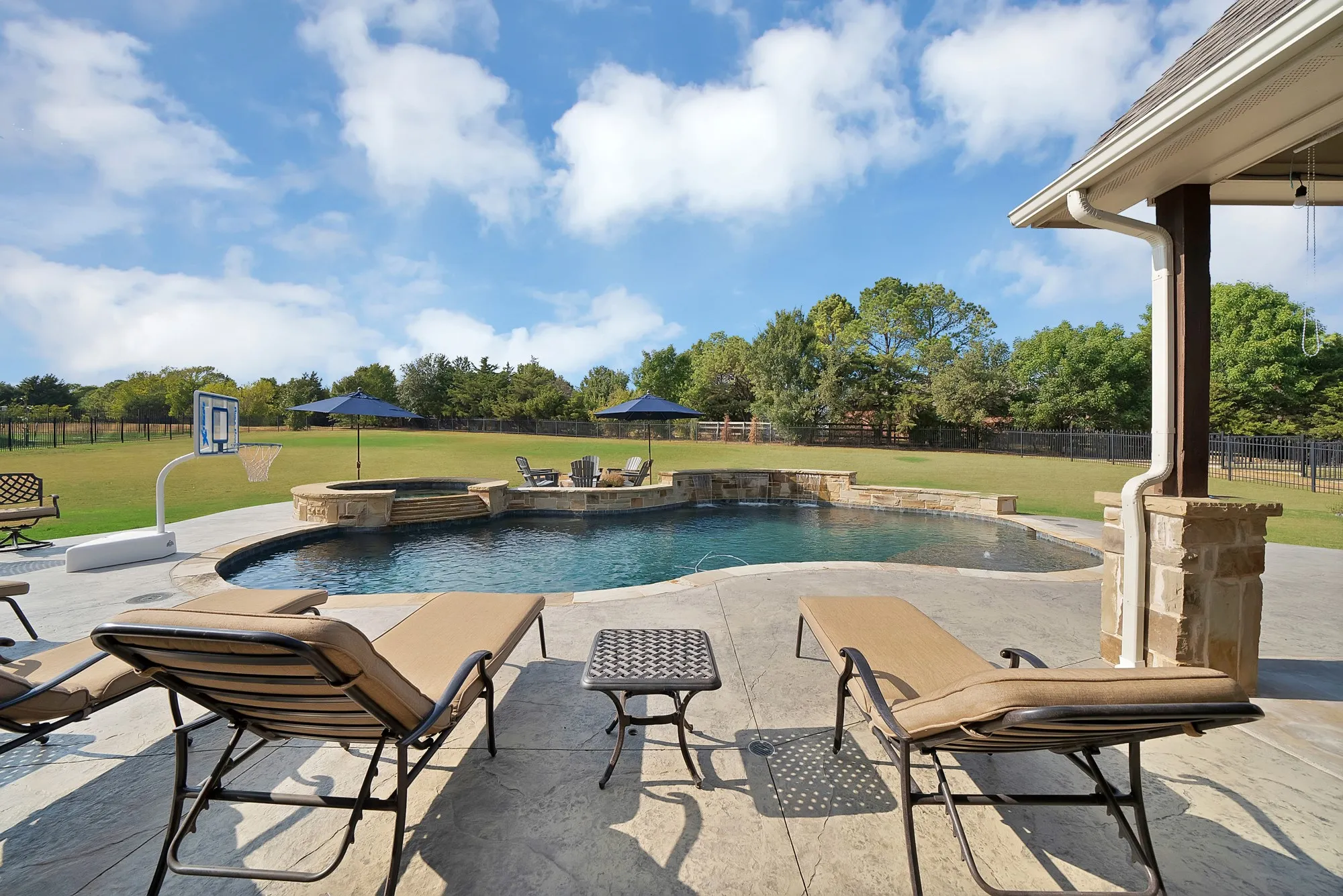 Swimming pool with an integrated hot tub and stone surround