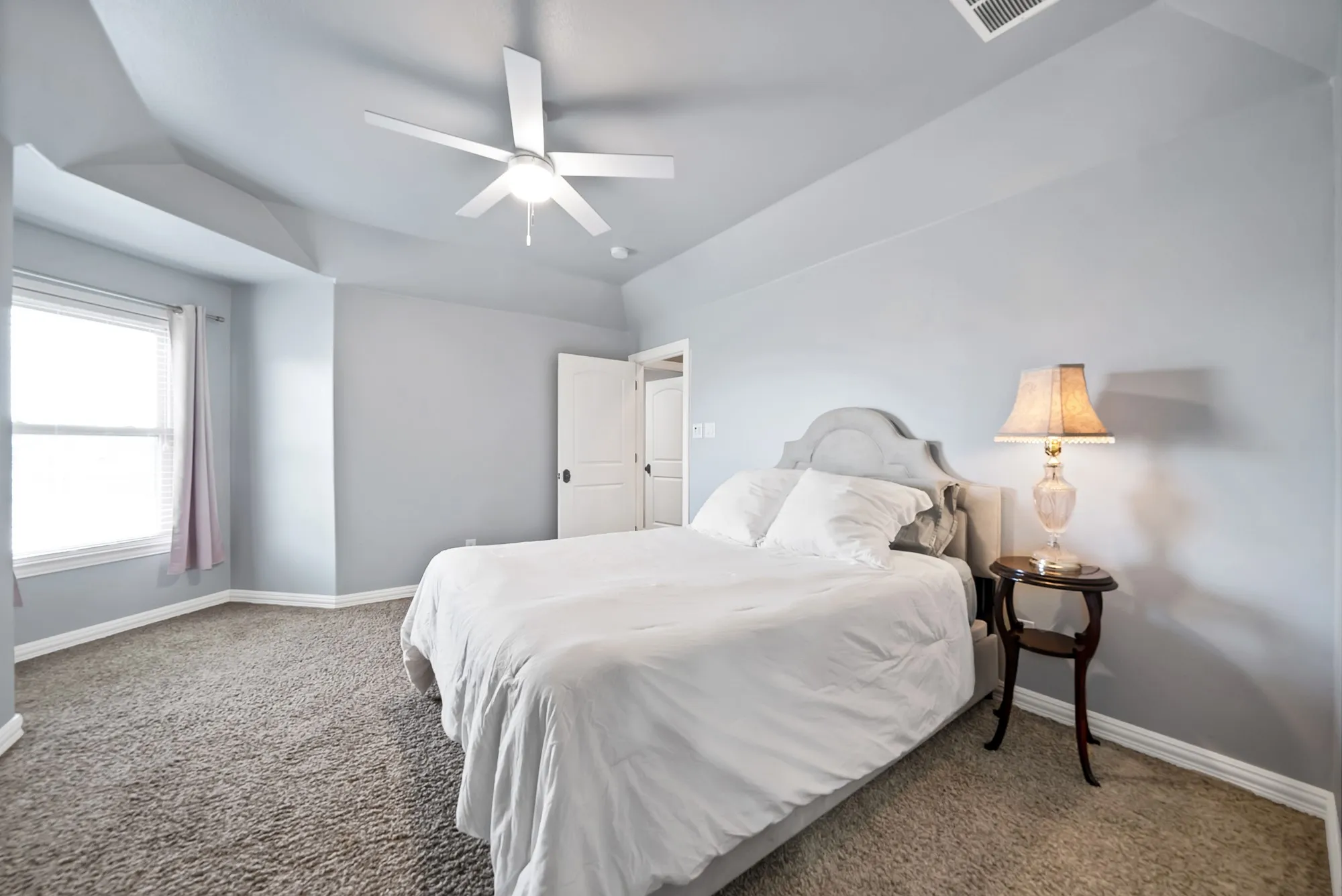 Tray ceiling with a ceiling fan, carpeted flooring, window with blinds, and white doors