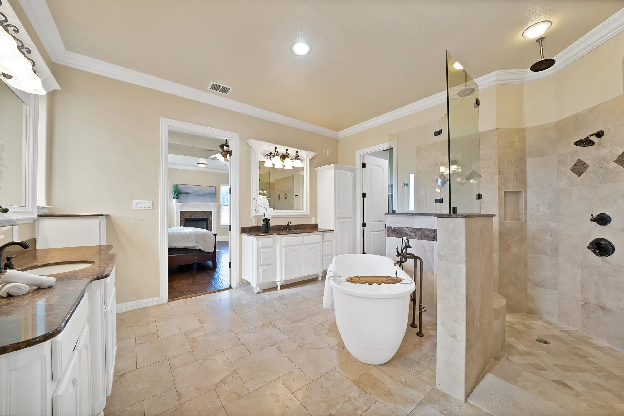Dual vanity with integrated sinks, freestanding soaking tub, and a glass-enclosed walk-in shower with multiple shower heads