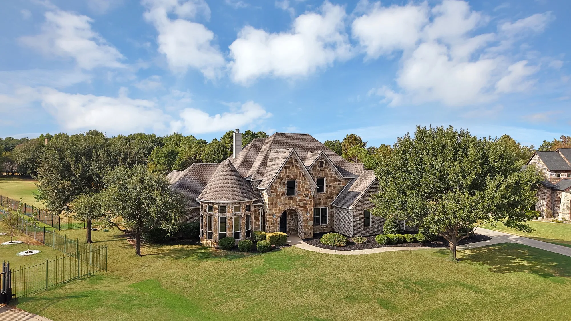 Stone and brick exterior with a turret, multi-gabled roof, and extensive landscaping