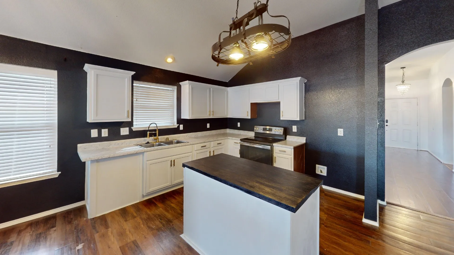Kitchen featuring white cabinetry, a central island with a wood-finish countertop, wood-finish flooring, and a stainless steel range