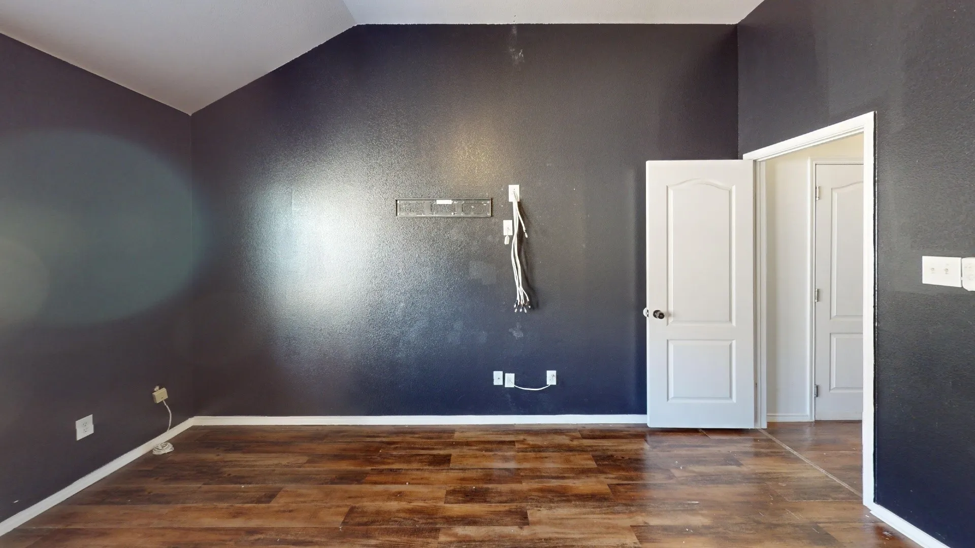 Wood-finish flooring with dark accent walls and white trim