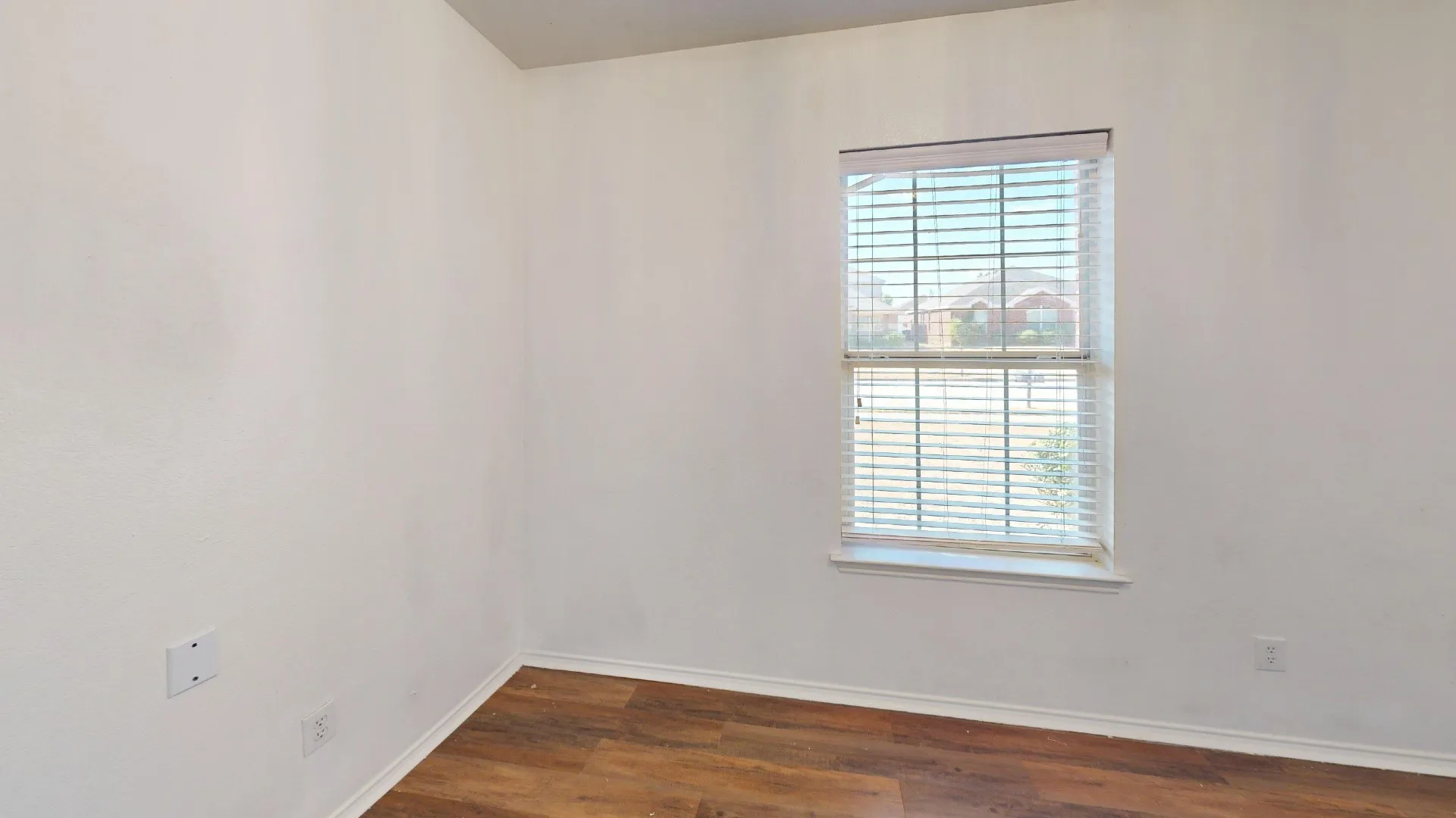 Wood-finish flooring with white baseboards and neutral wall tones