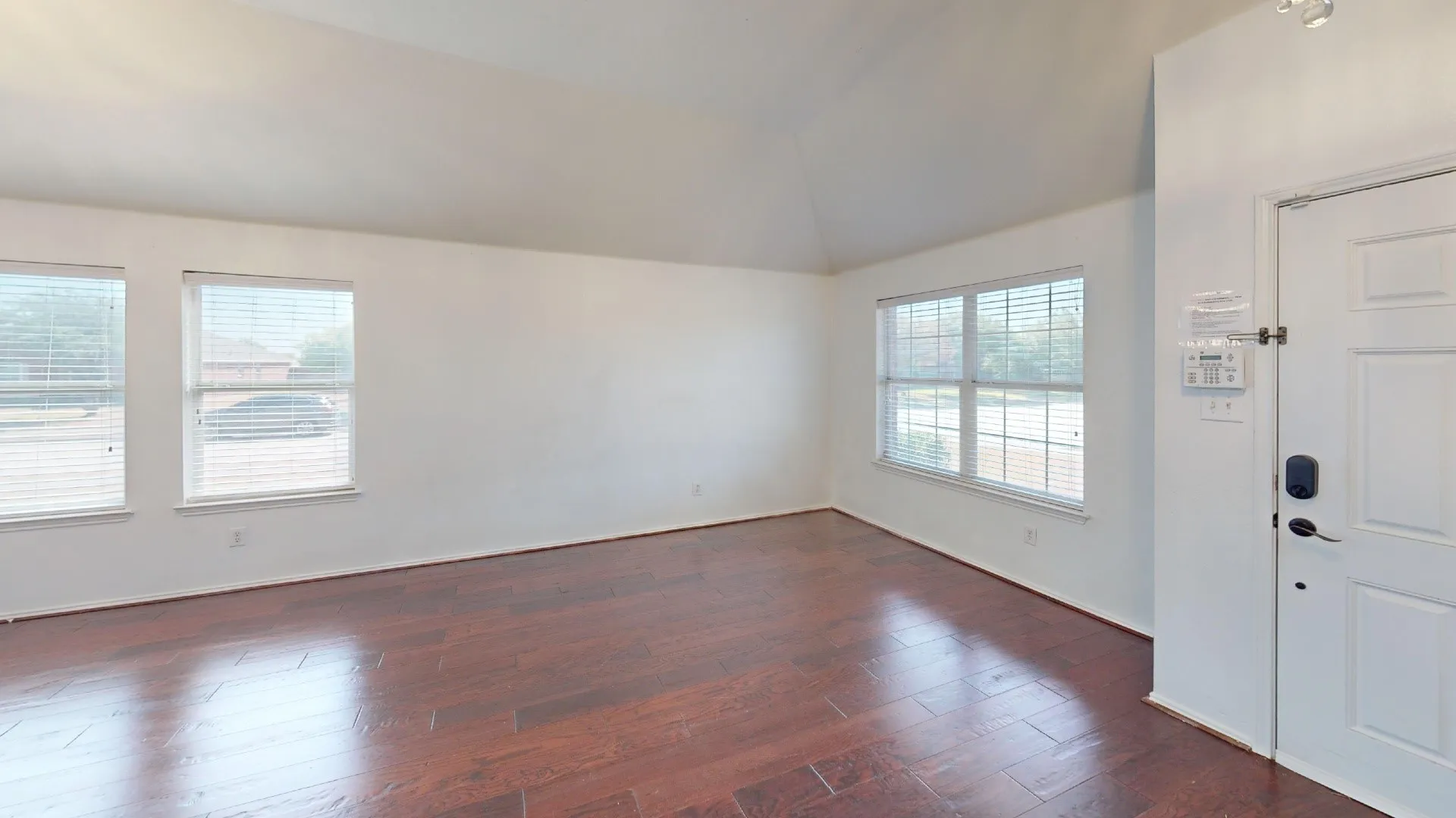 Vaulted ceiling with recessed lighting, wood-finish flooring, and multiple windows with blinds