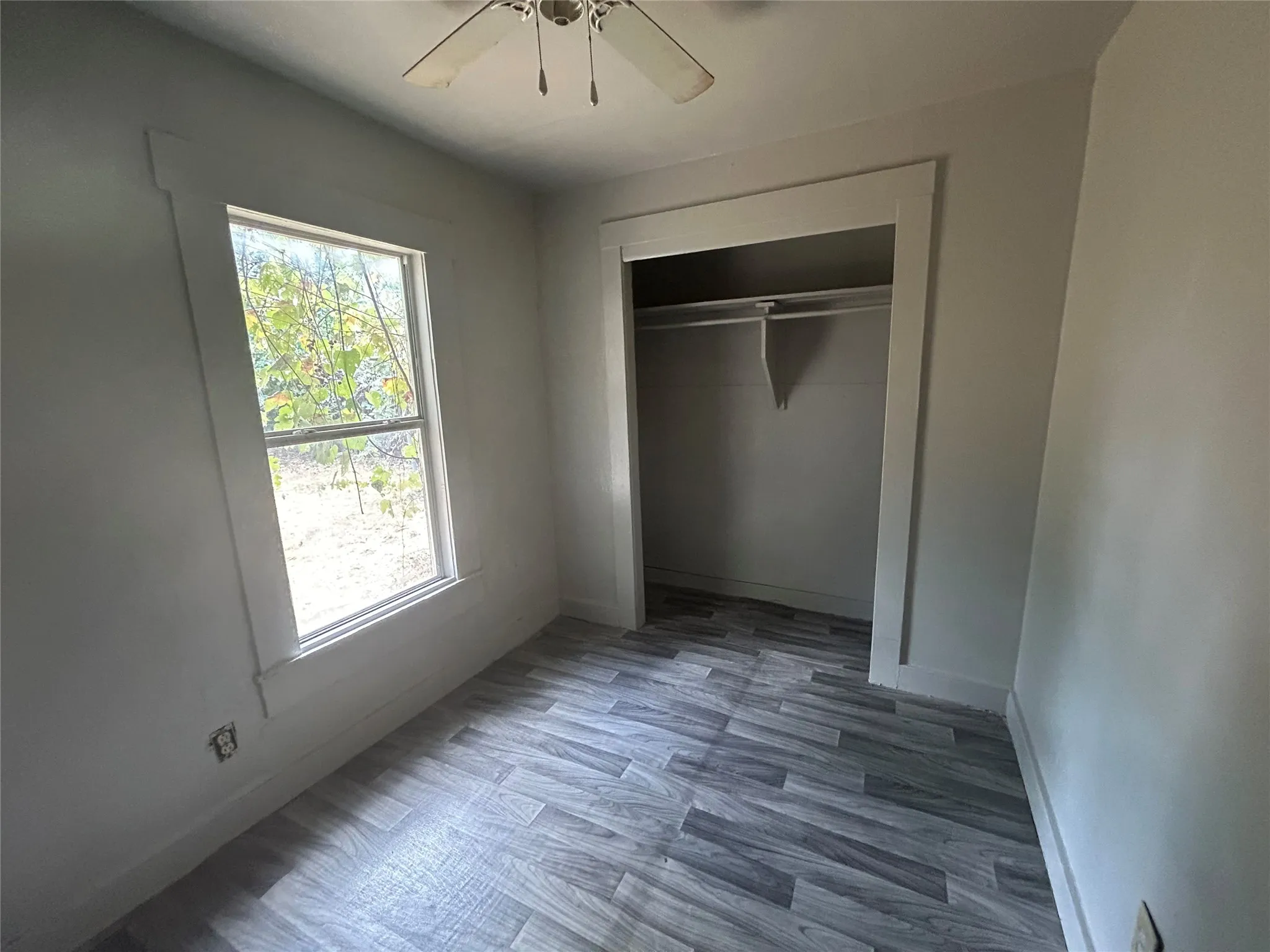Wood-finish flooring, single window, integrated closet with shelving, ceiling fan