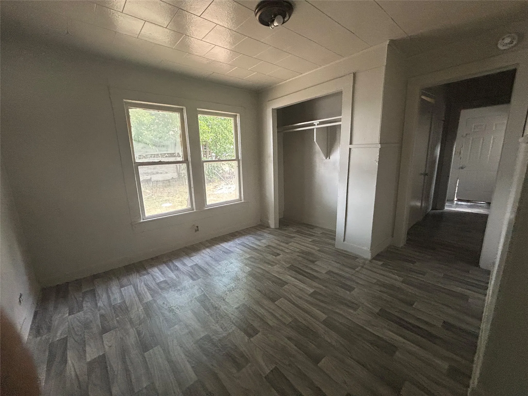 Wood-finish flooring, dual windows, and an open closet with built-in shelving