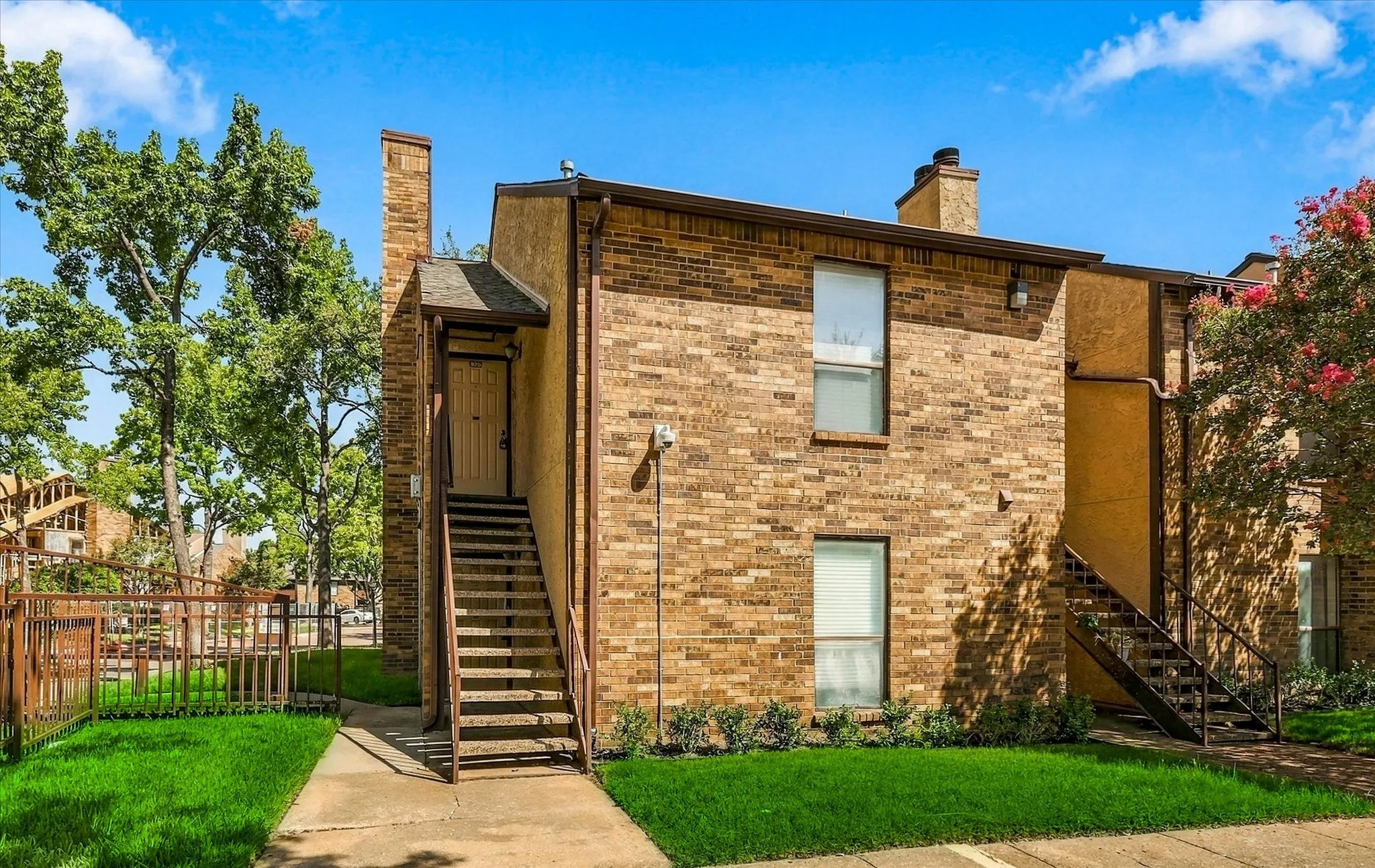 Brick exterior facade with a prominent chimney, upper-level entrance with covered stairs, and ground-level entryway