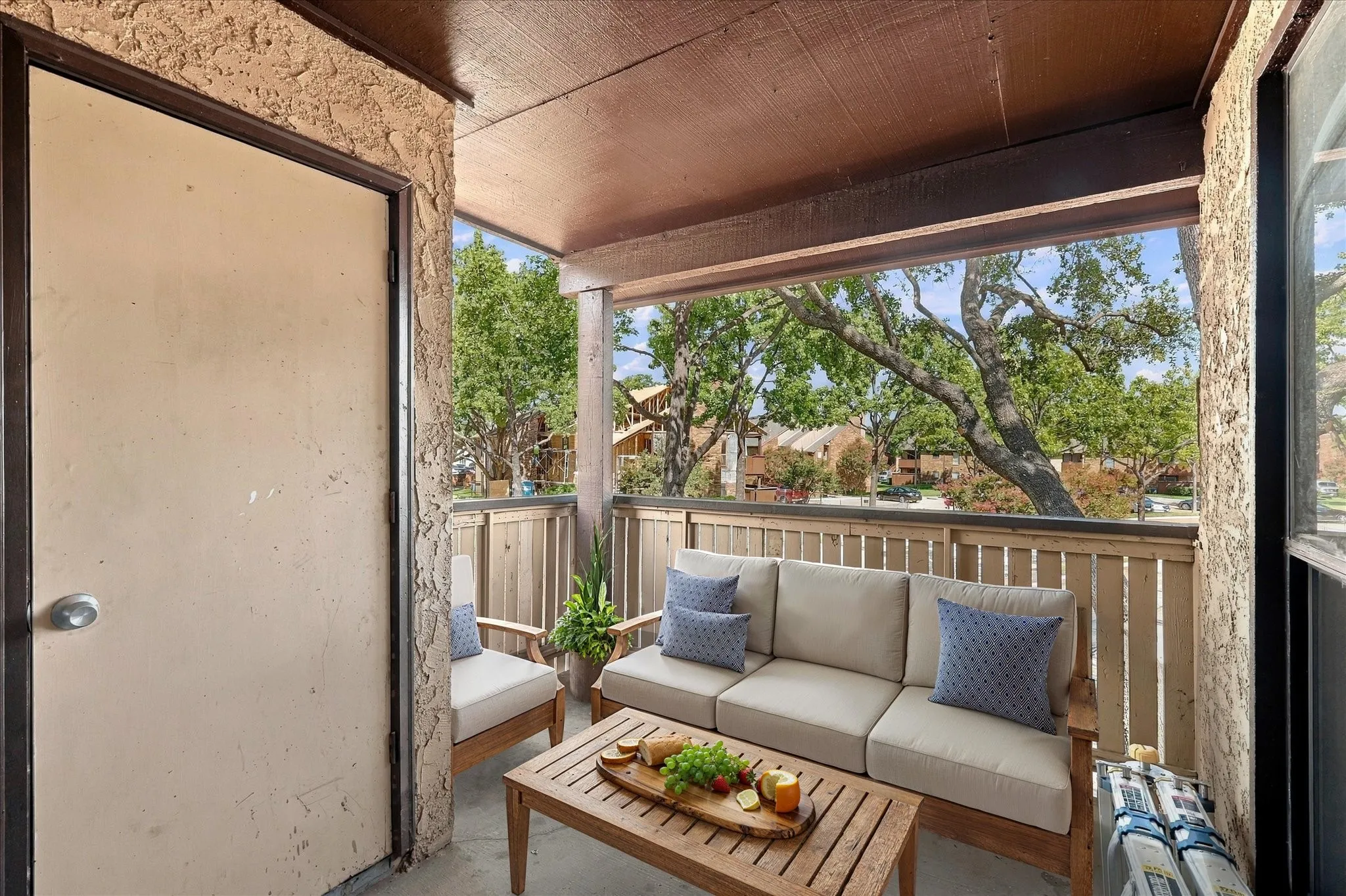 Virtually stagedCovered outdoor patio with a textured ceiling, privacy wall, and wood railing
