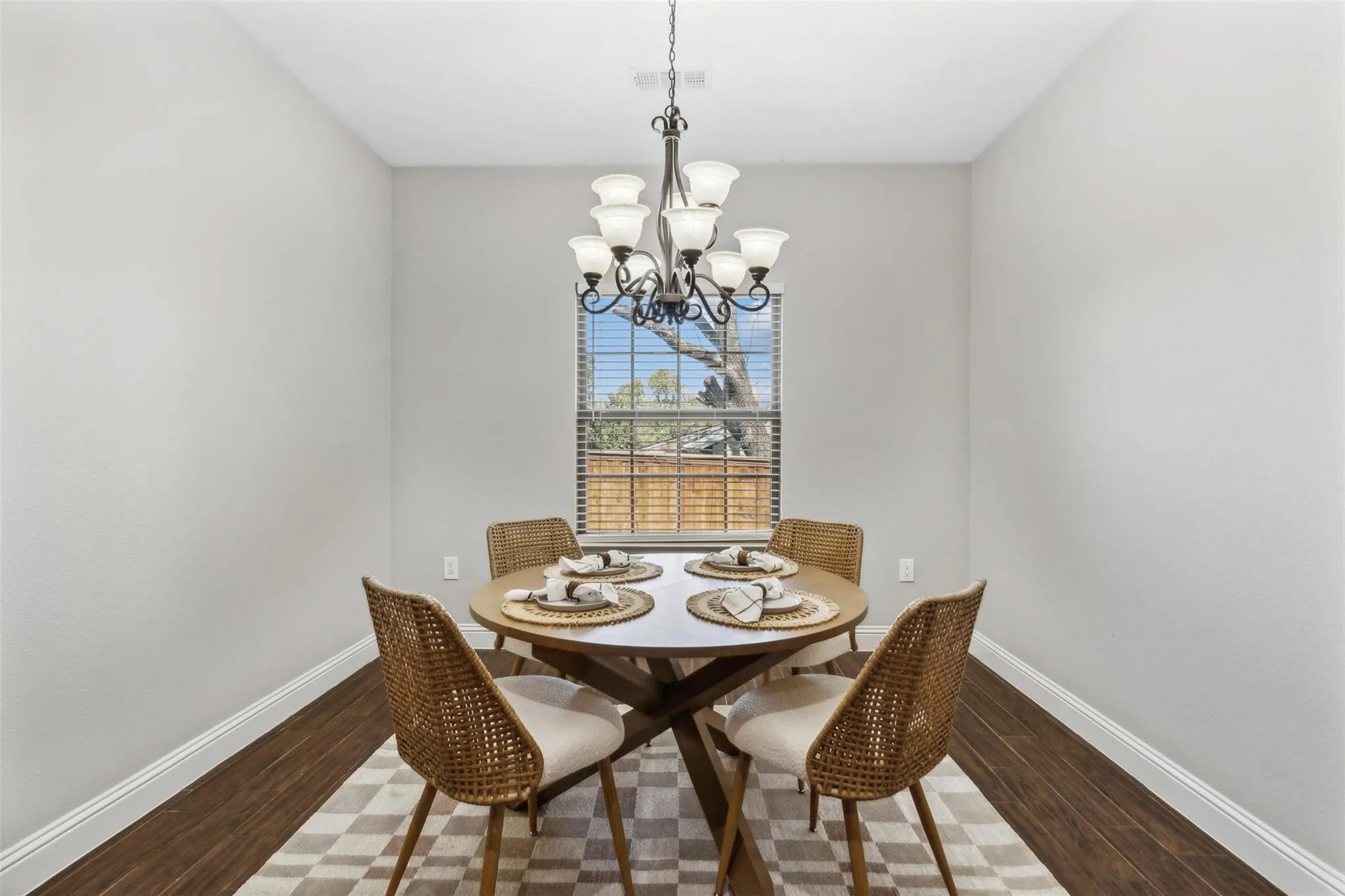Recessed room with wood-finish flooring, a multi-light chandelier, and a window with blinds