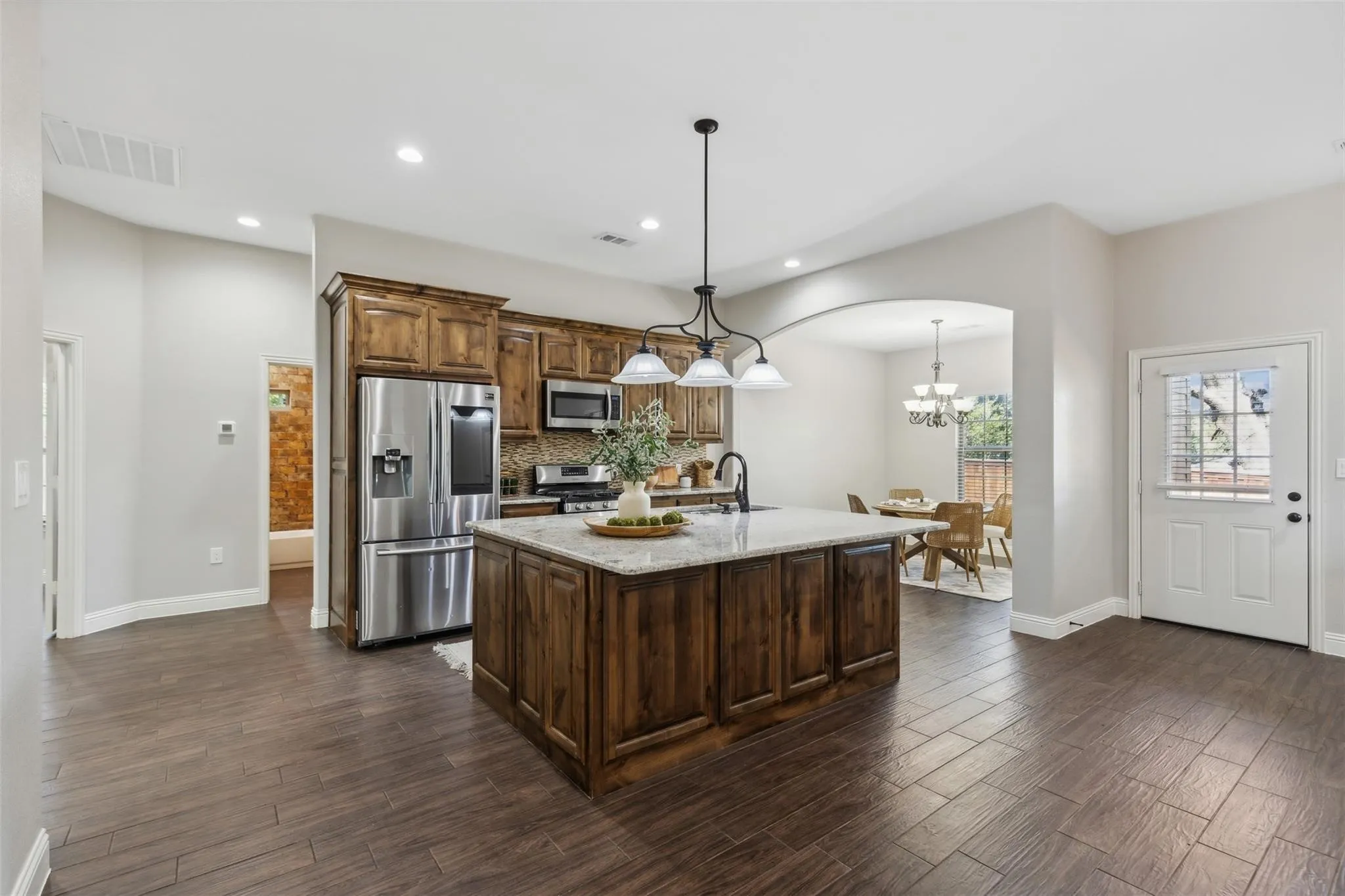 Kitchen featuring a central island with countertop, wood cabinetry, stainless steel appliances, and wood-finish flooring