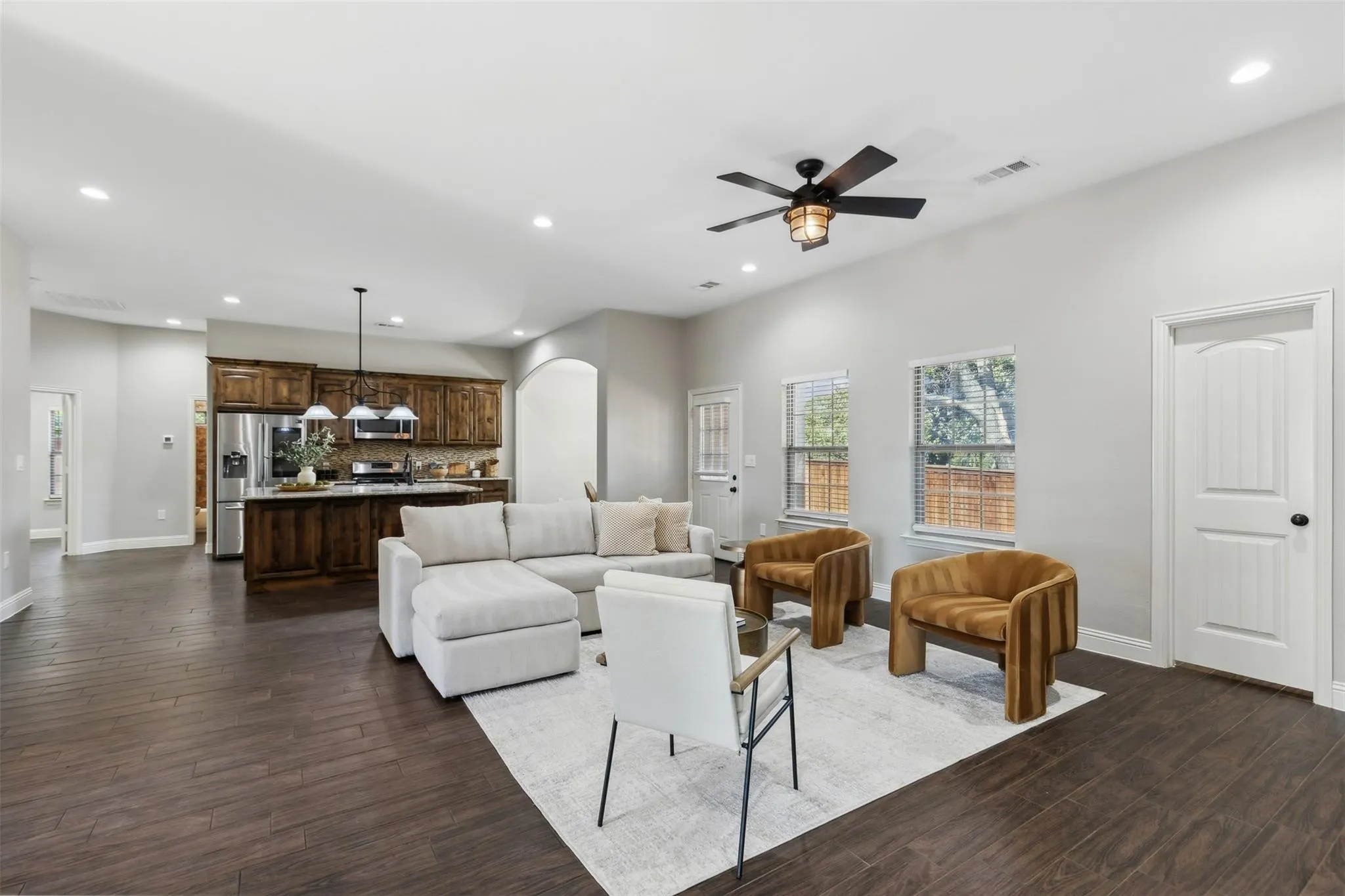 Open-concept living space with dark wood-finish flooring, recessed lighting, and a ceiling fan