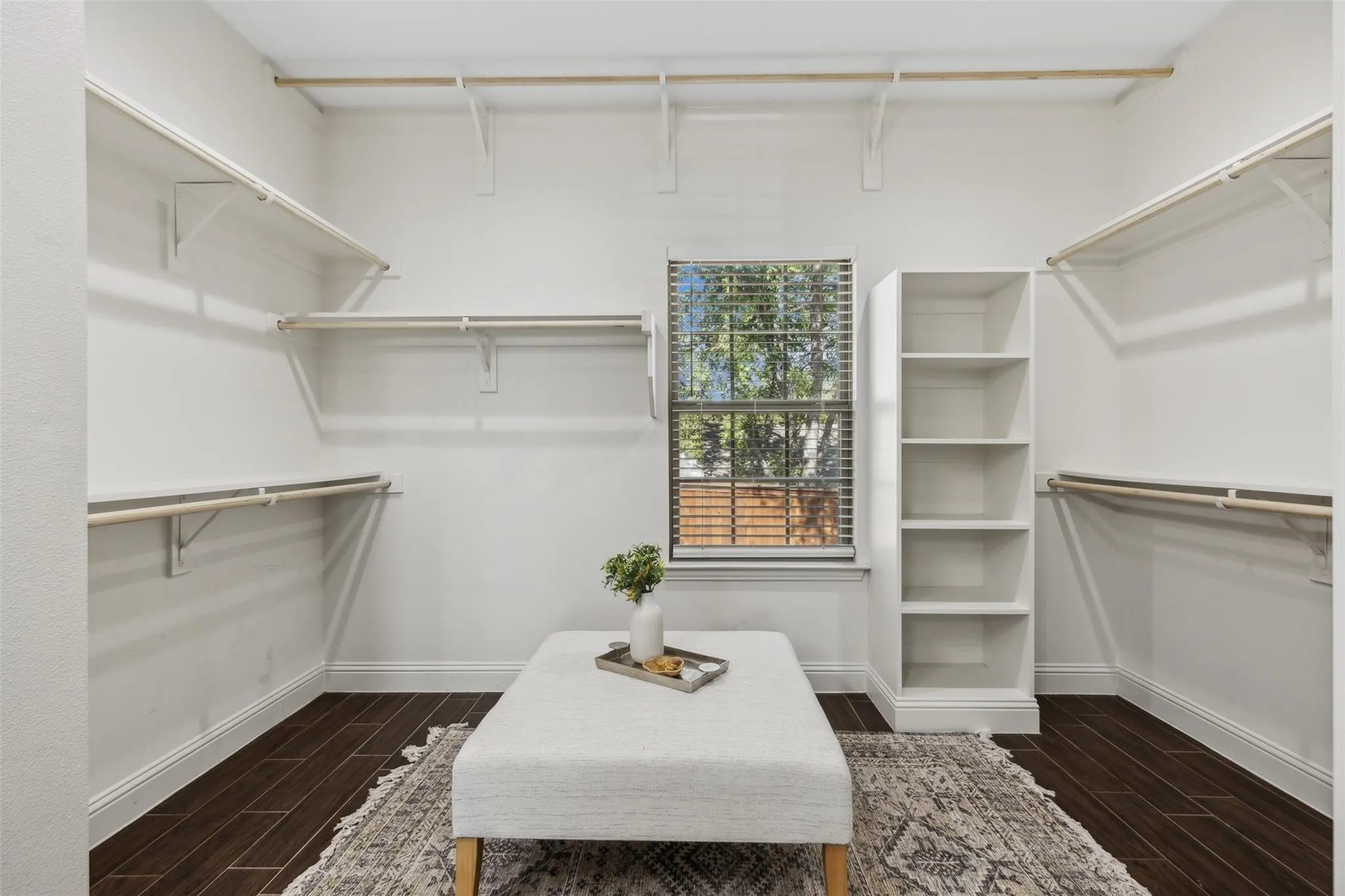Built-in shelving and hanging rods, built-in open storage unit, window with blinds, and wood-finish flooring