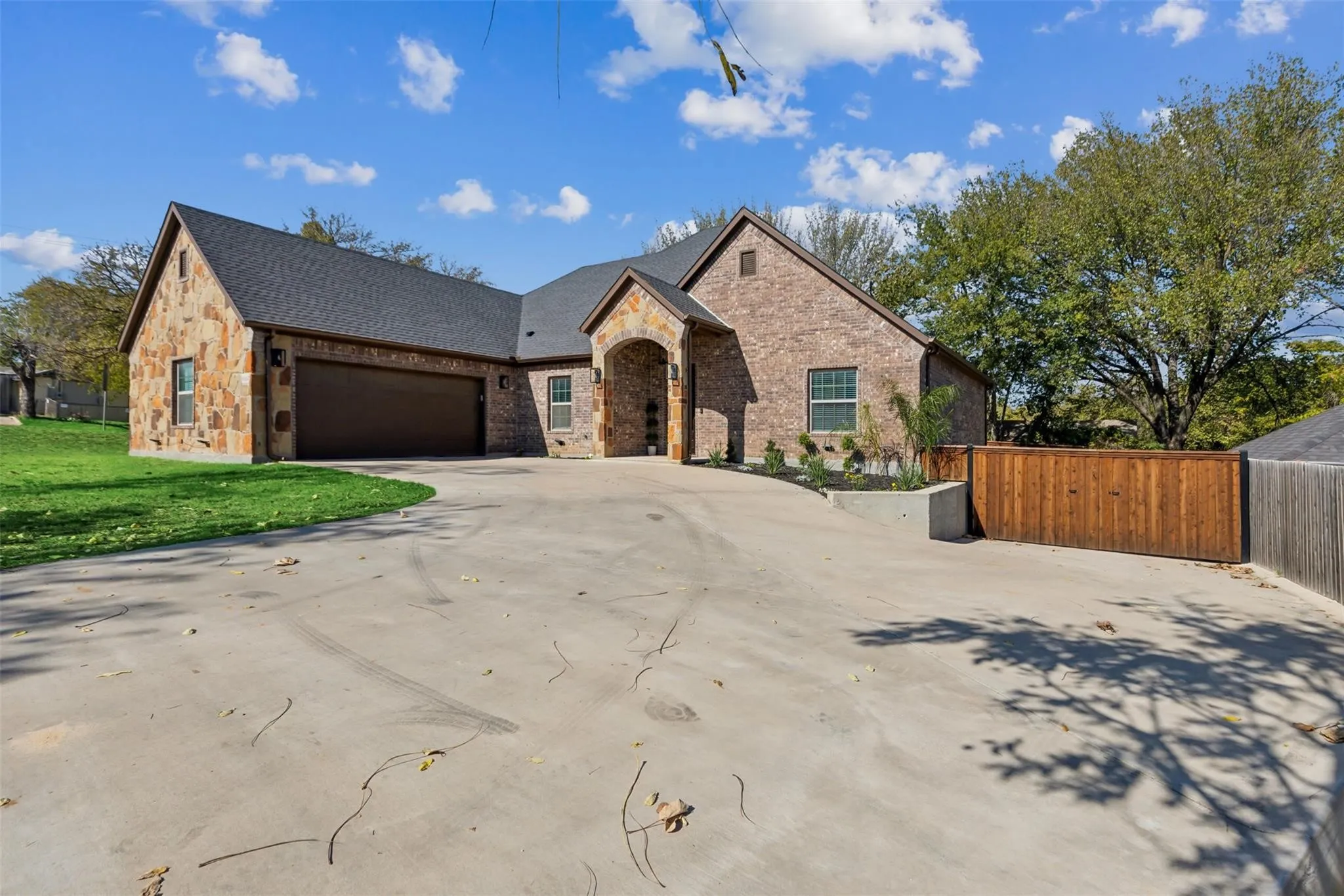 Brick and stone exterior with a dark shingle roof