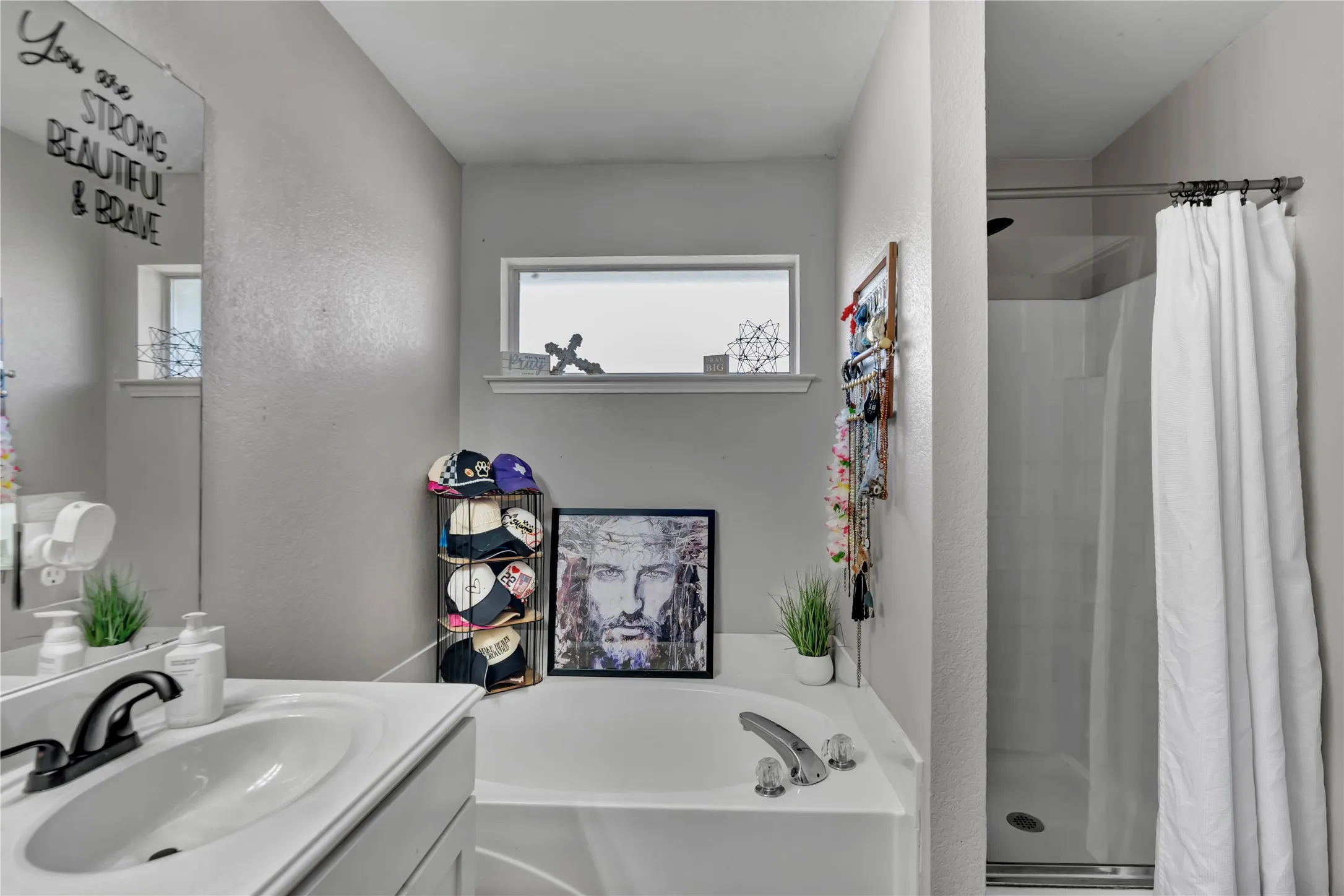 Vanity with integrated sink and dark-finish faucet, soaking tub with deck-mounted fixtures, and separate shower stall