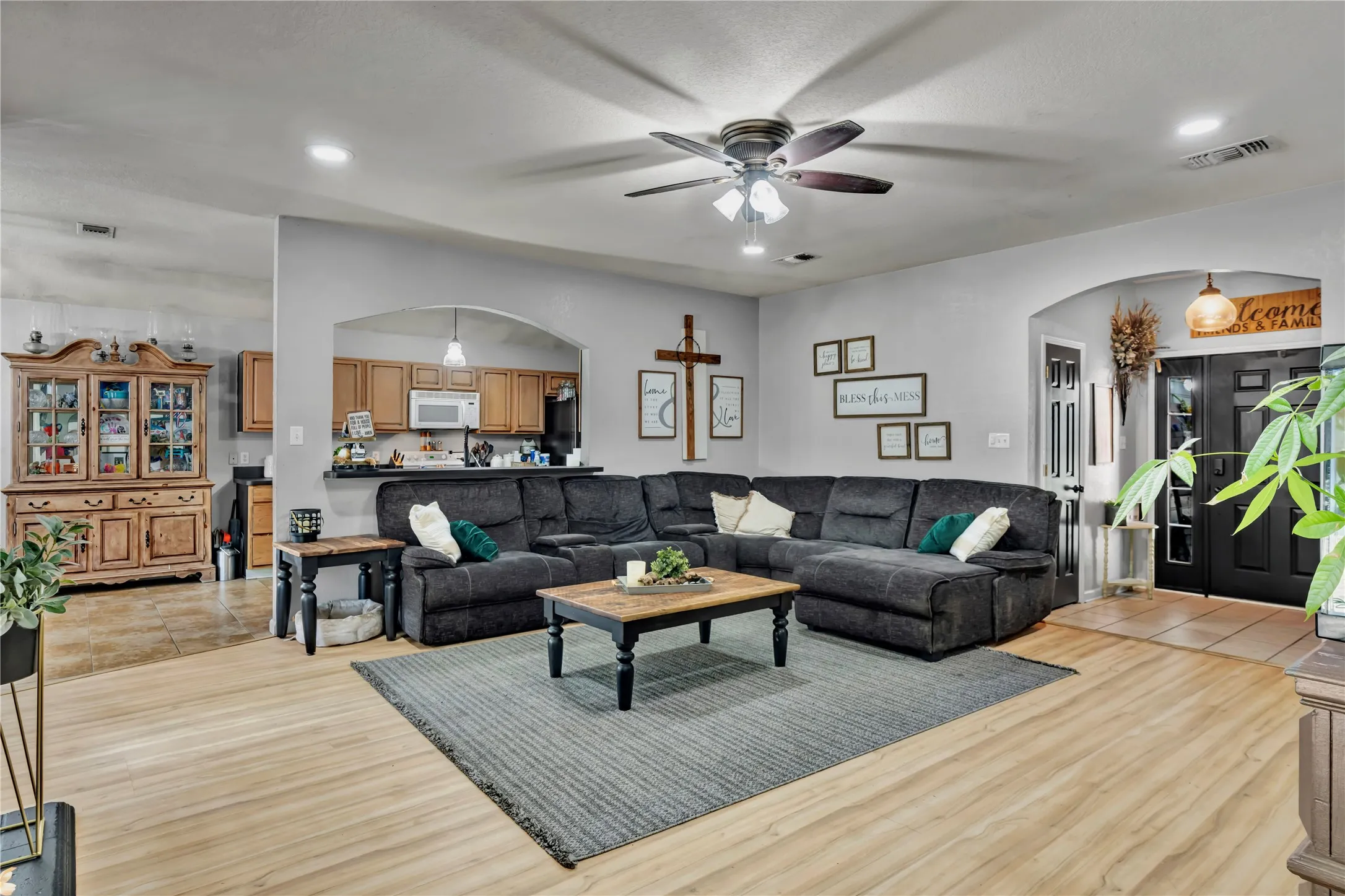 Wood-finish flooring throughout, featuring recessed lighting and a ceiling fan