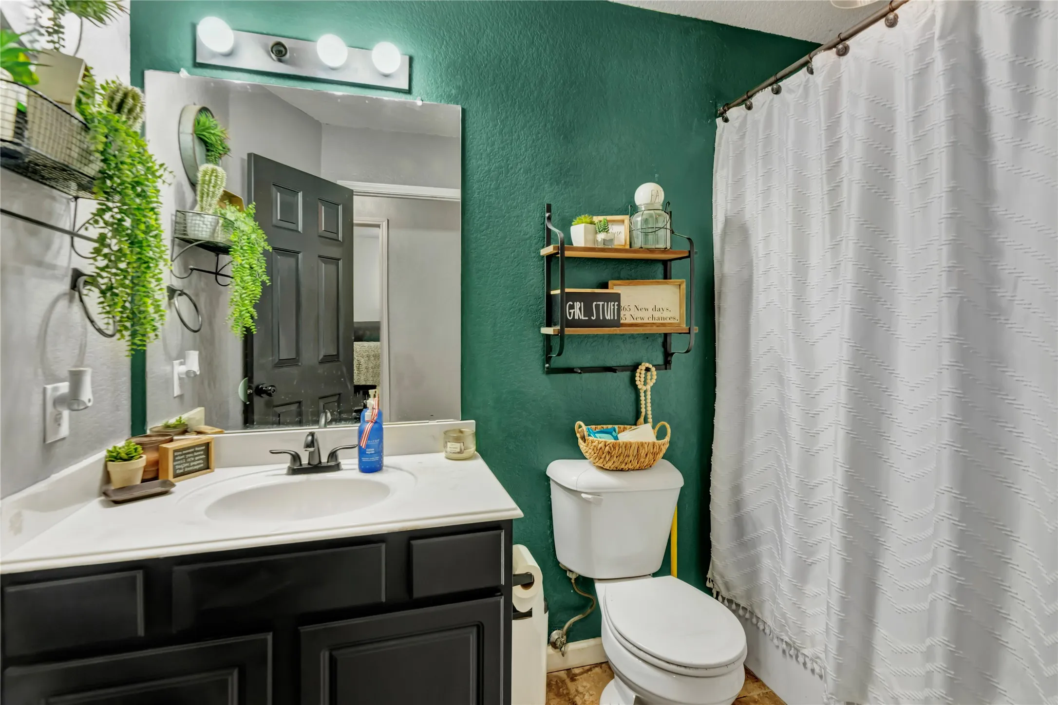 Vanity with an integrated sink, wall-mounted light fixture, and a large wall mirror