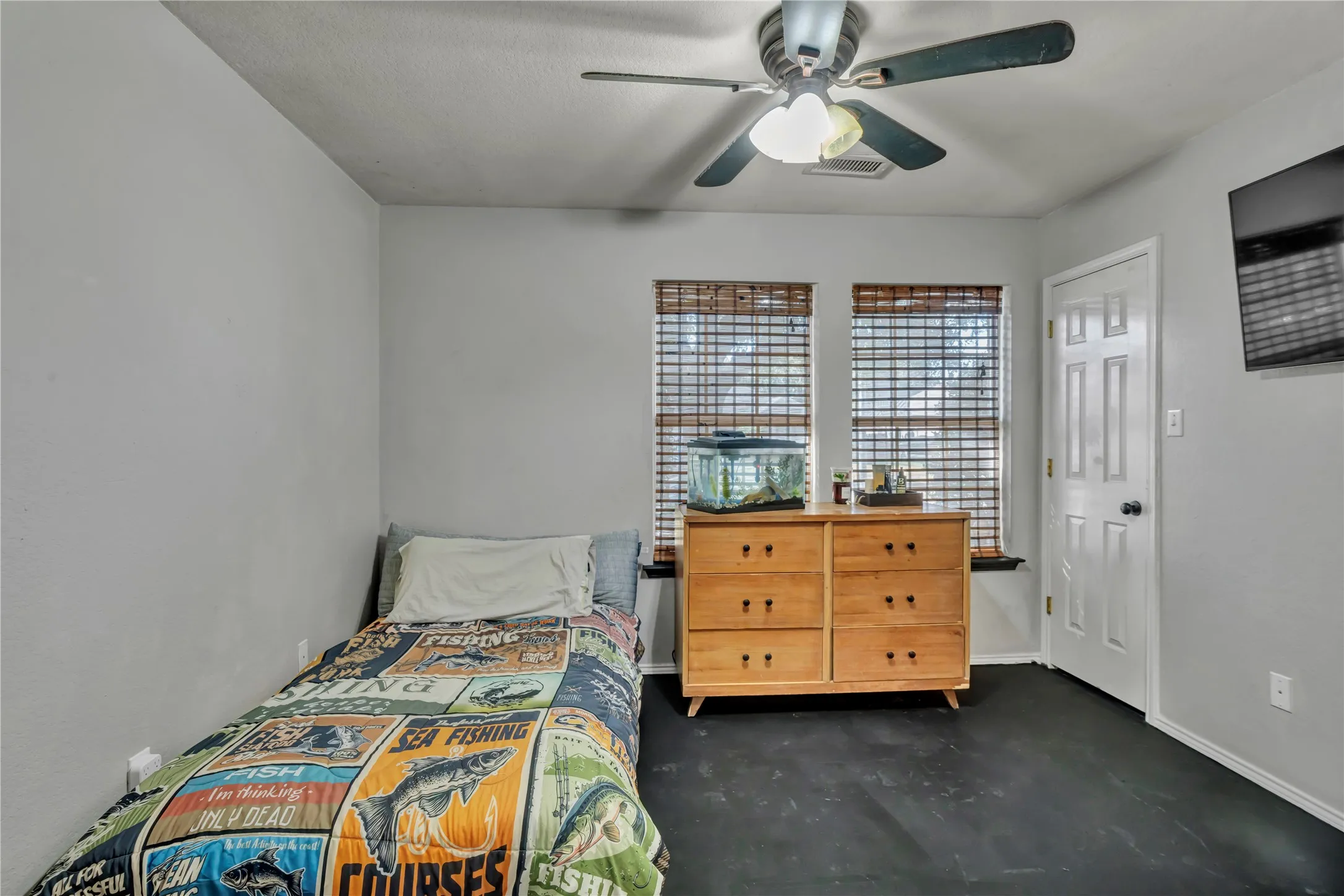 Neutral wall tones, dual windows with blinds, a ceiling fan, and dark-toned flooring