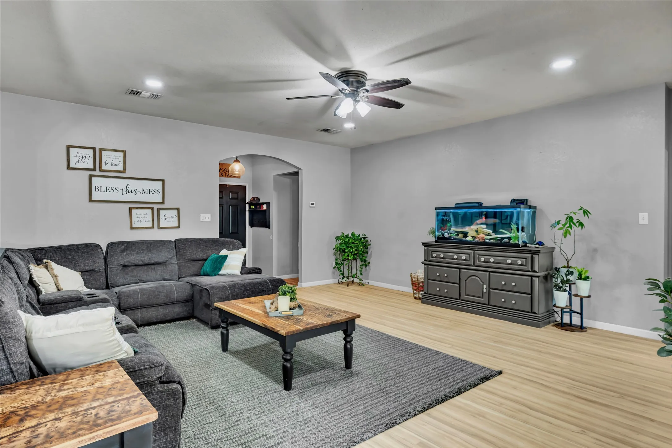 Spacious living area featuring light wood-finish flooring, recessed lighting, and a ceiling fan