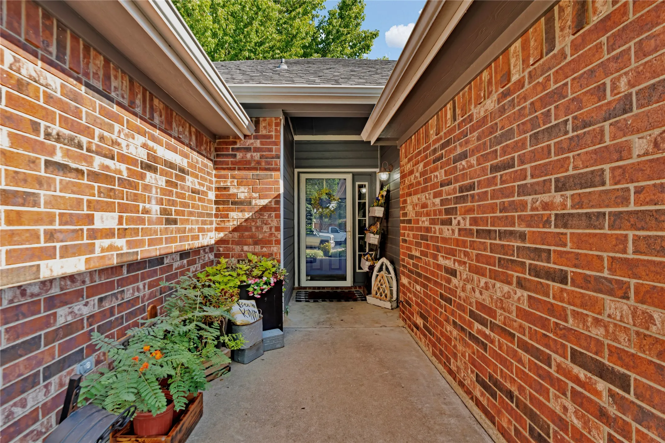 Brick exterior with dark siding accents, a concrete walkway, and a glass-paneled entry door