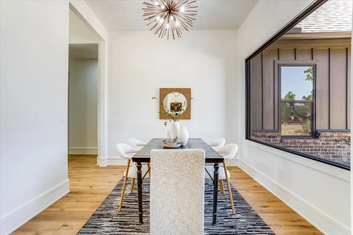 LVP flooring, crisp white walls, contemporary sputnik chandelier, built-in window with black trim, and a dark-toned dining table