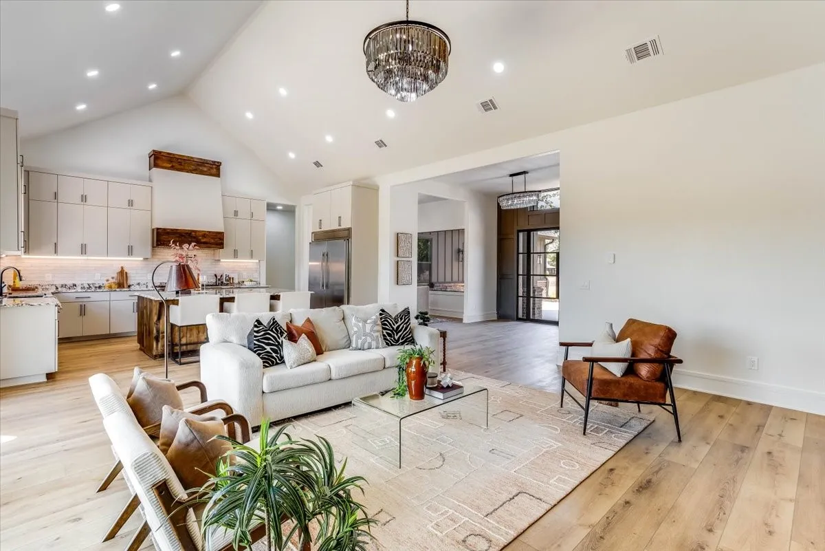 Vaulted ceiling, recessed lighting, wood-finish flooring, built-in kitchen cabinetry, and a large kitchen island