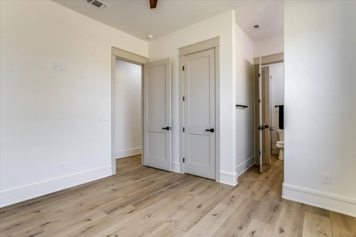 Light wood-finish flooring, white walls, and modern two-panel doors with matte black hardware
